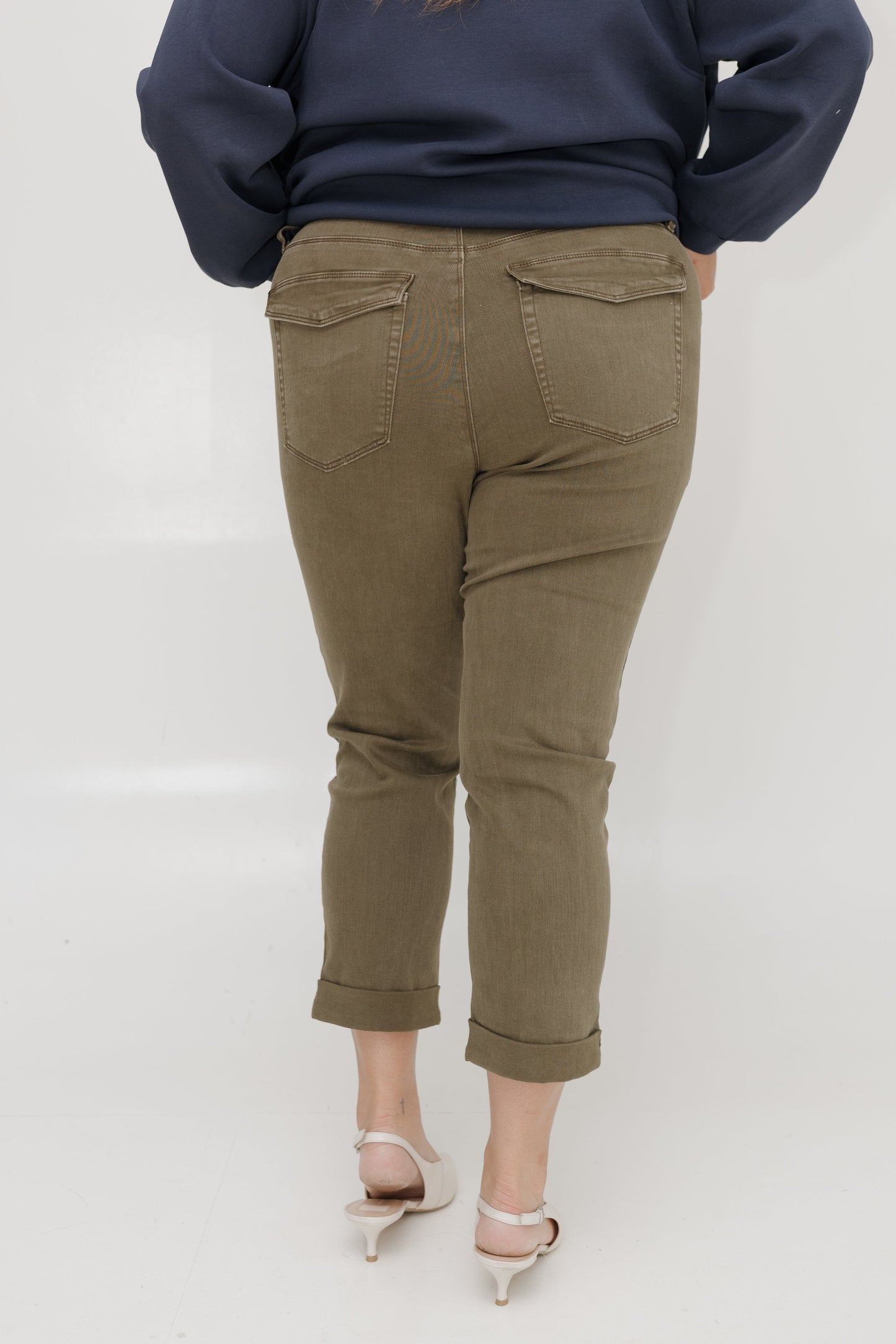 Person wearing olive green pants and a navy blue sweater on a white background