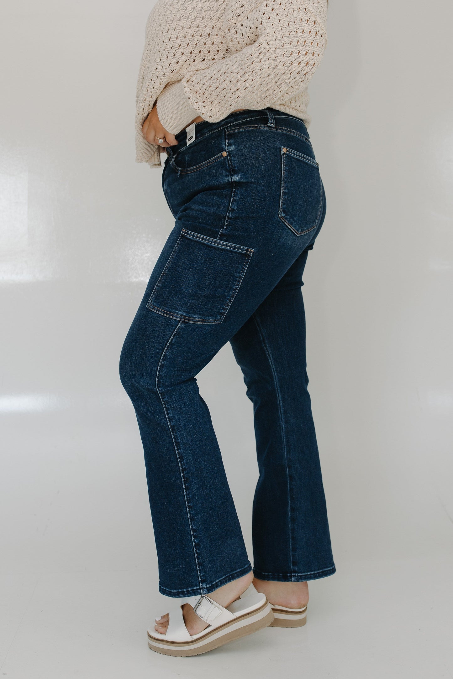 Person wearing blue jeans and a beige sweater on a white background
