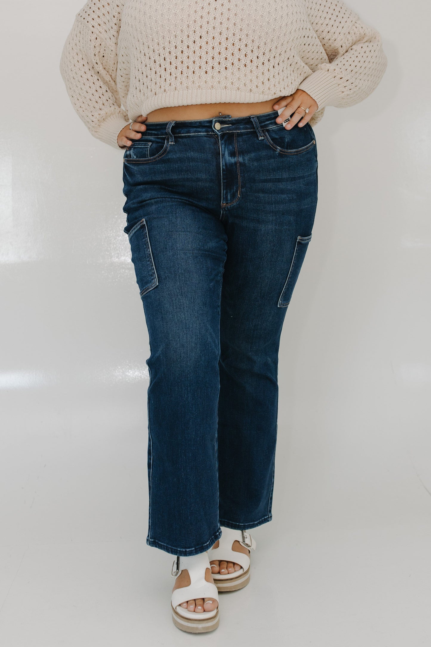 Person wearing blue jeans and a beige sweater on a white background