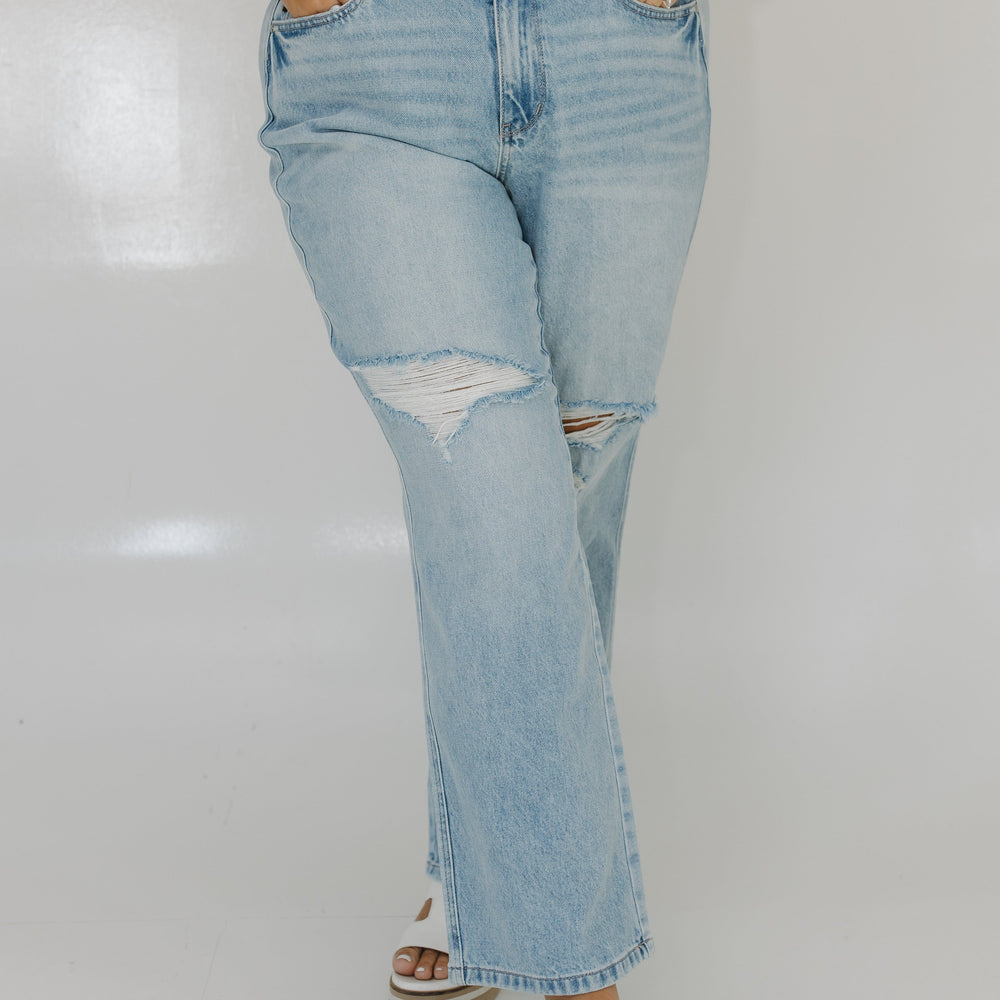 Person wearing light blue ripped jeans and a striped shirt on a white background