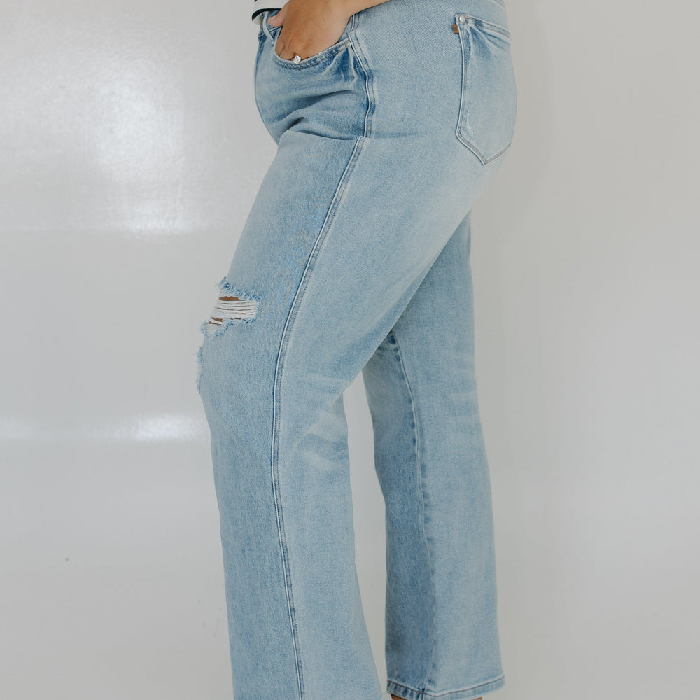 Person wearing light blue jeans and a striped shirt on a plain background