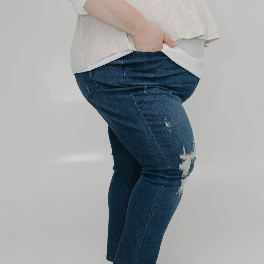 Person wearing blue jeans and a white top on a plain background