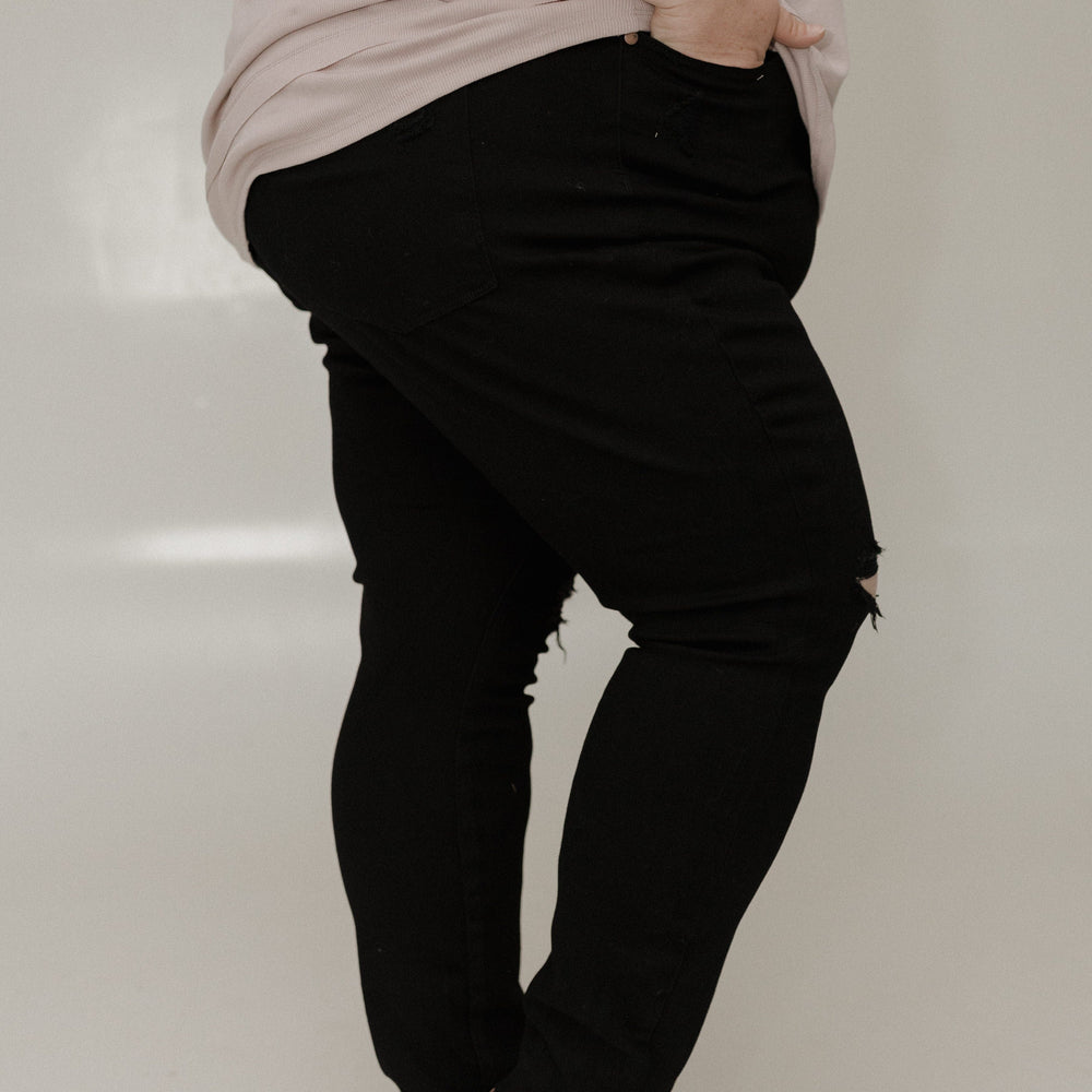 Person wearing black pants and a light-colored top on a white background