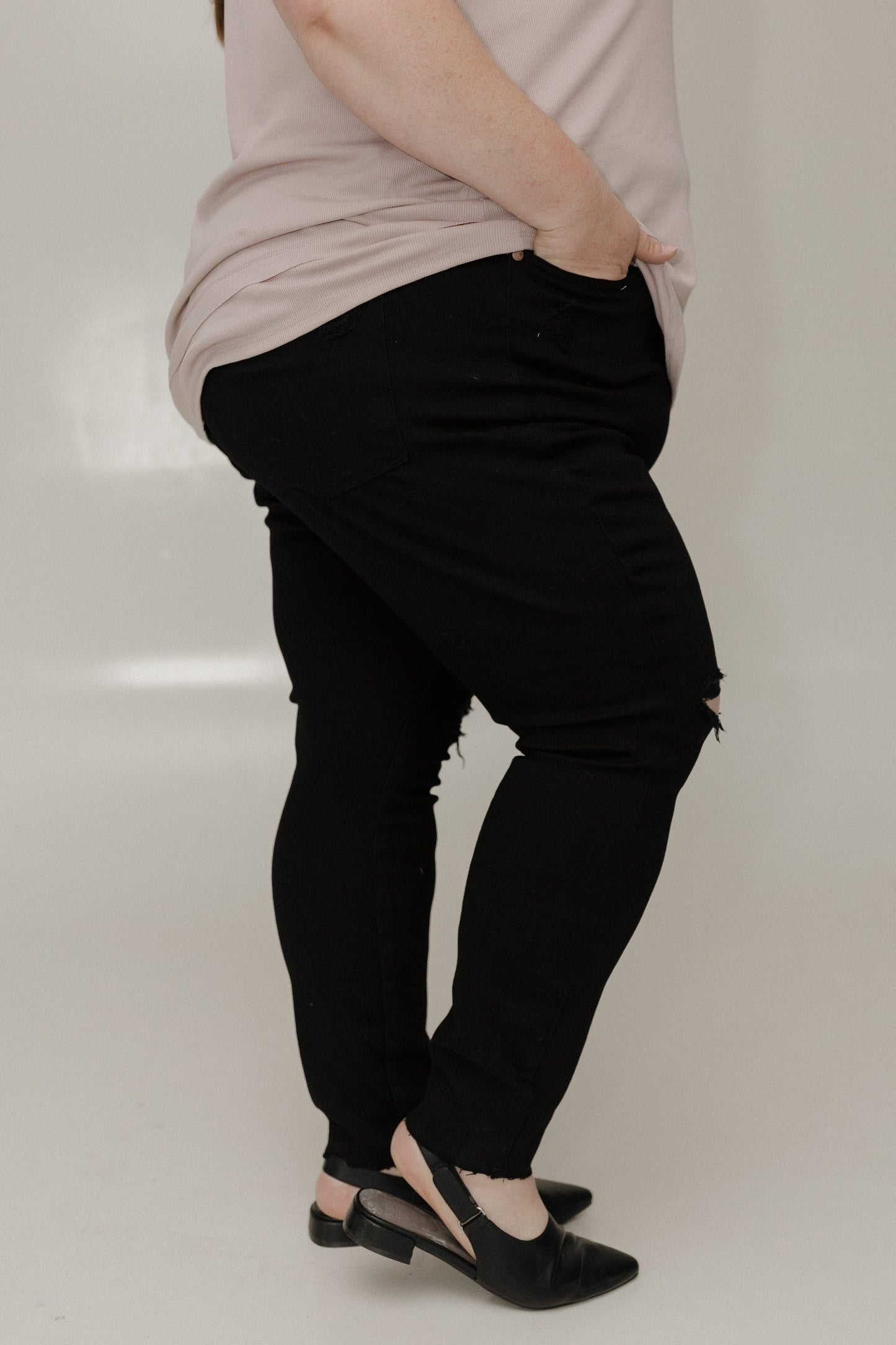 Person wearing black pants and a light-colored top on a white background