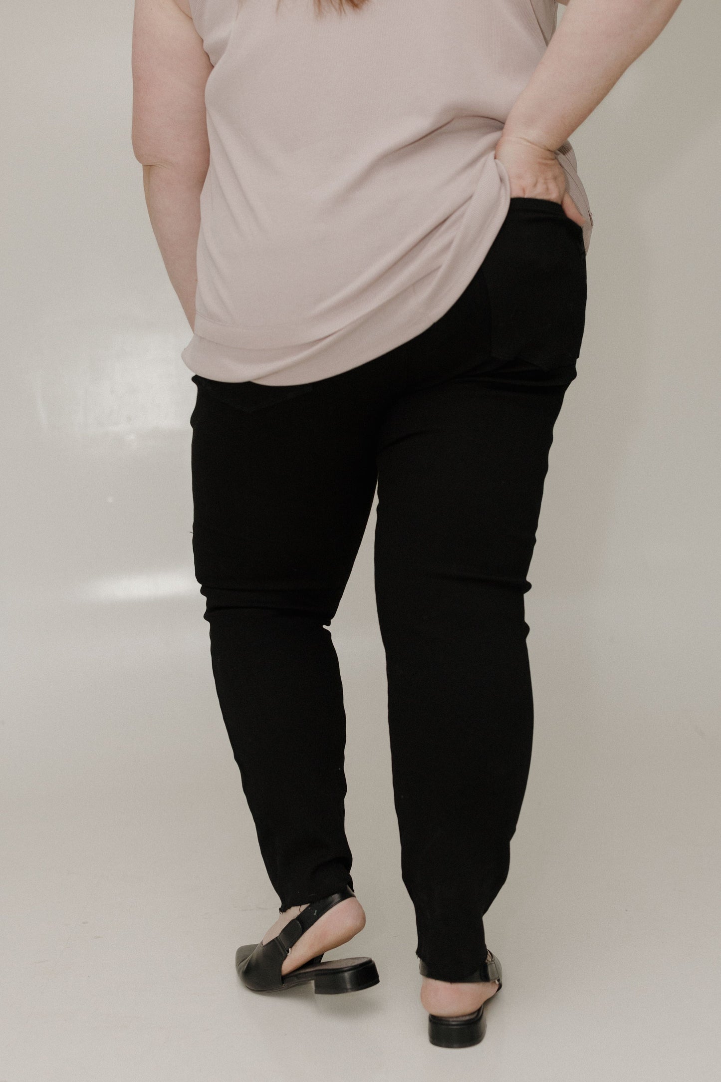 Person wearing a beige top and black pants on a plain background