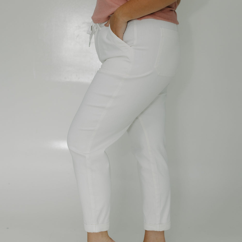 Person wearing light gray pants and a pink top on a plain background