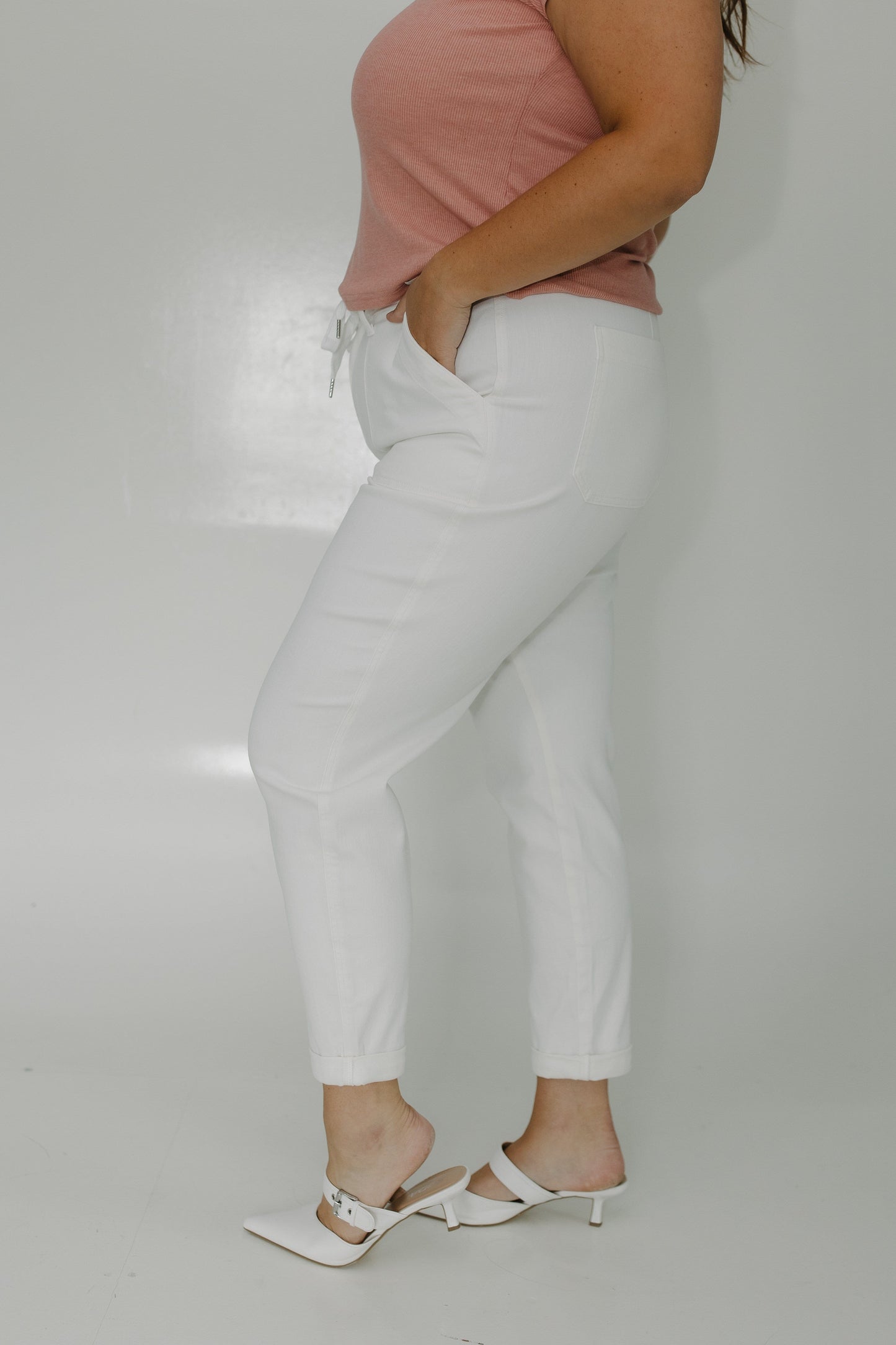 Person wearing light gray pants and a pink top on a plain background