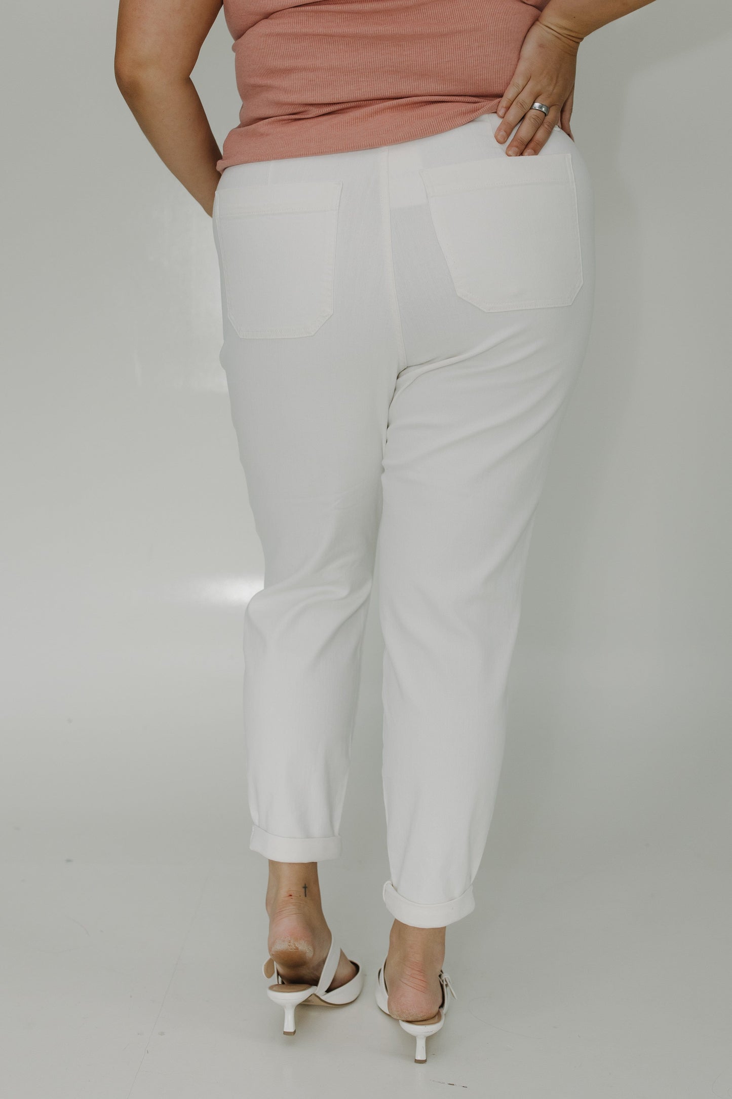 Person wearing white pants and a pink top on a plain background