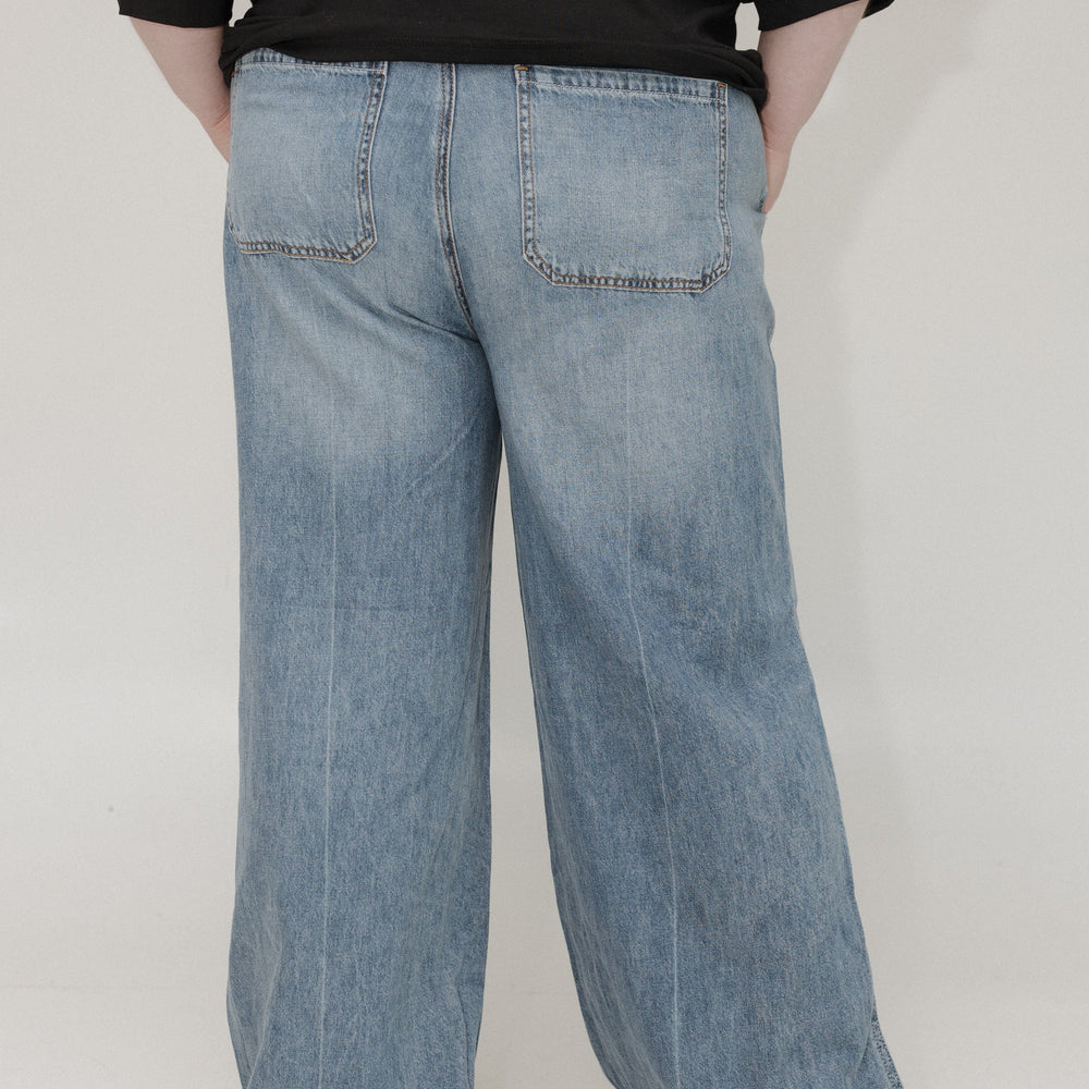 Person wearing light blue jeans and a black top on a white background