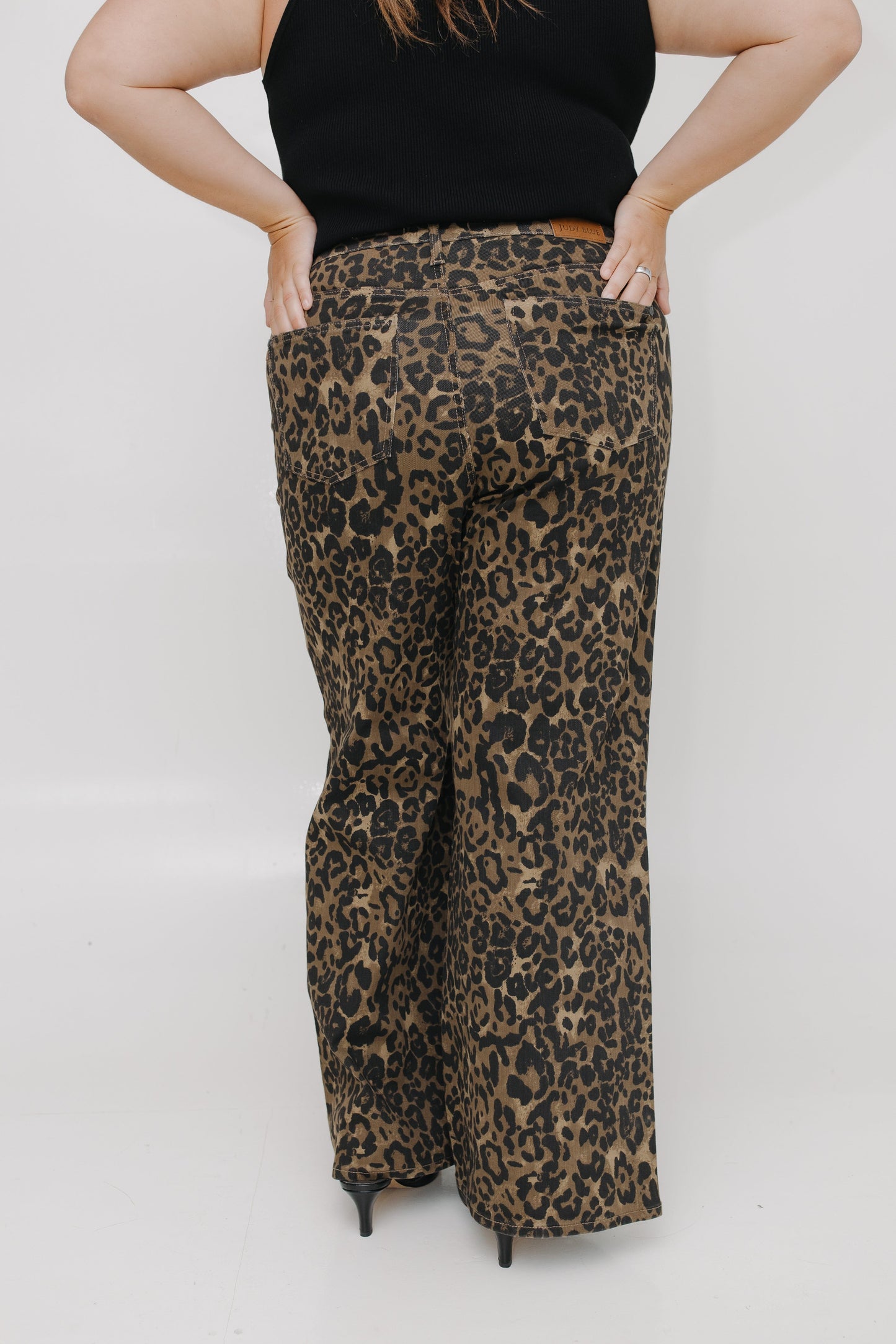 Person wearing leopard print pants and a black top on a white background