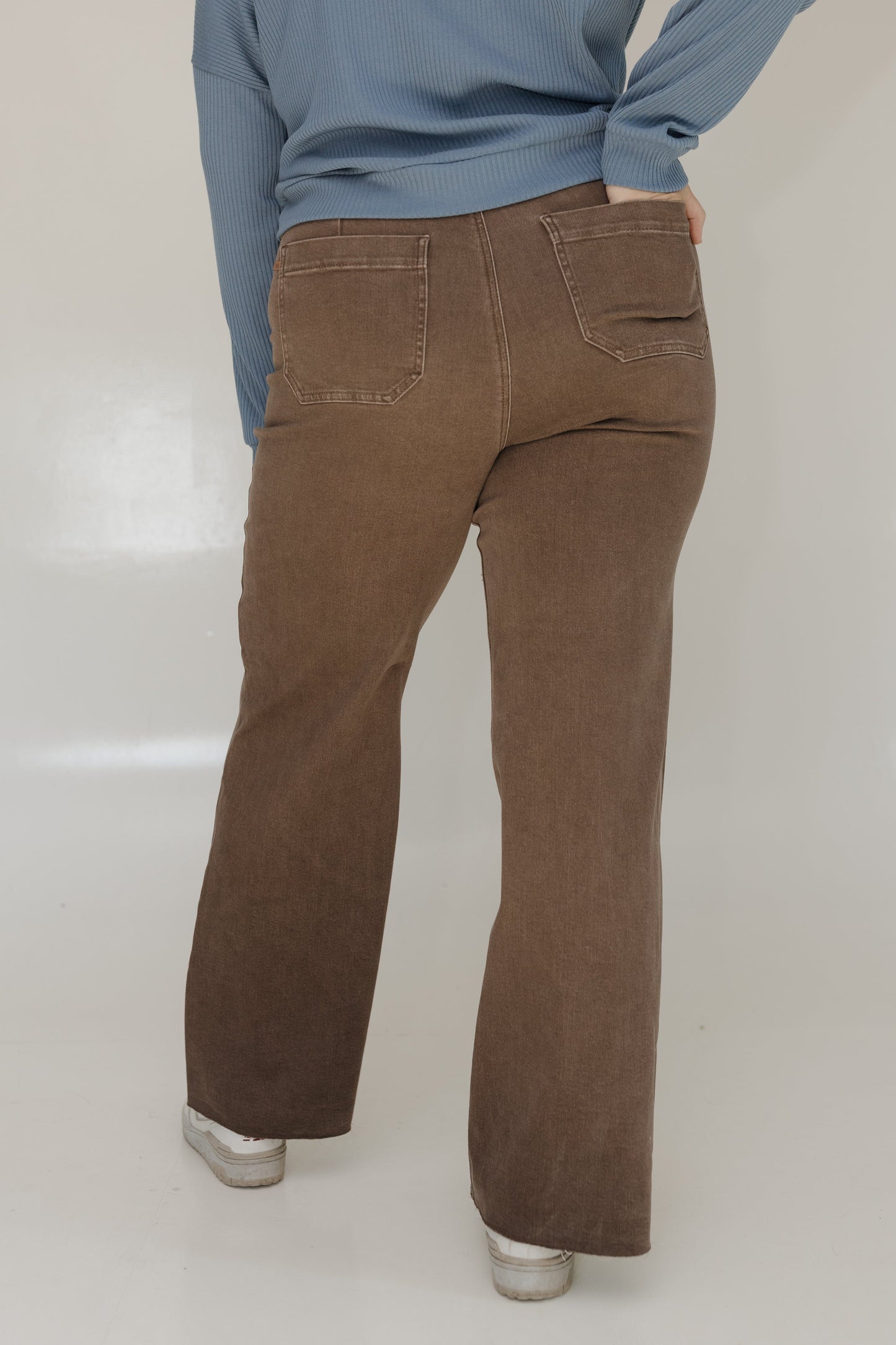 Person wearing brown pants and a blue sweater on a white background