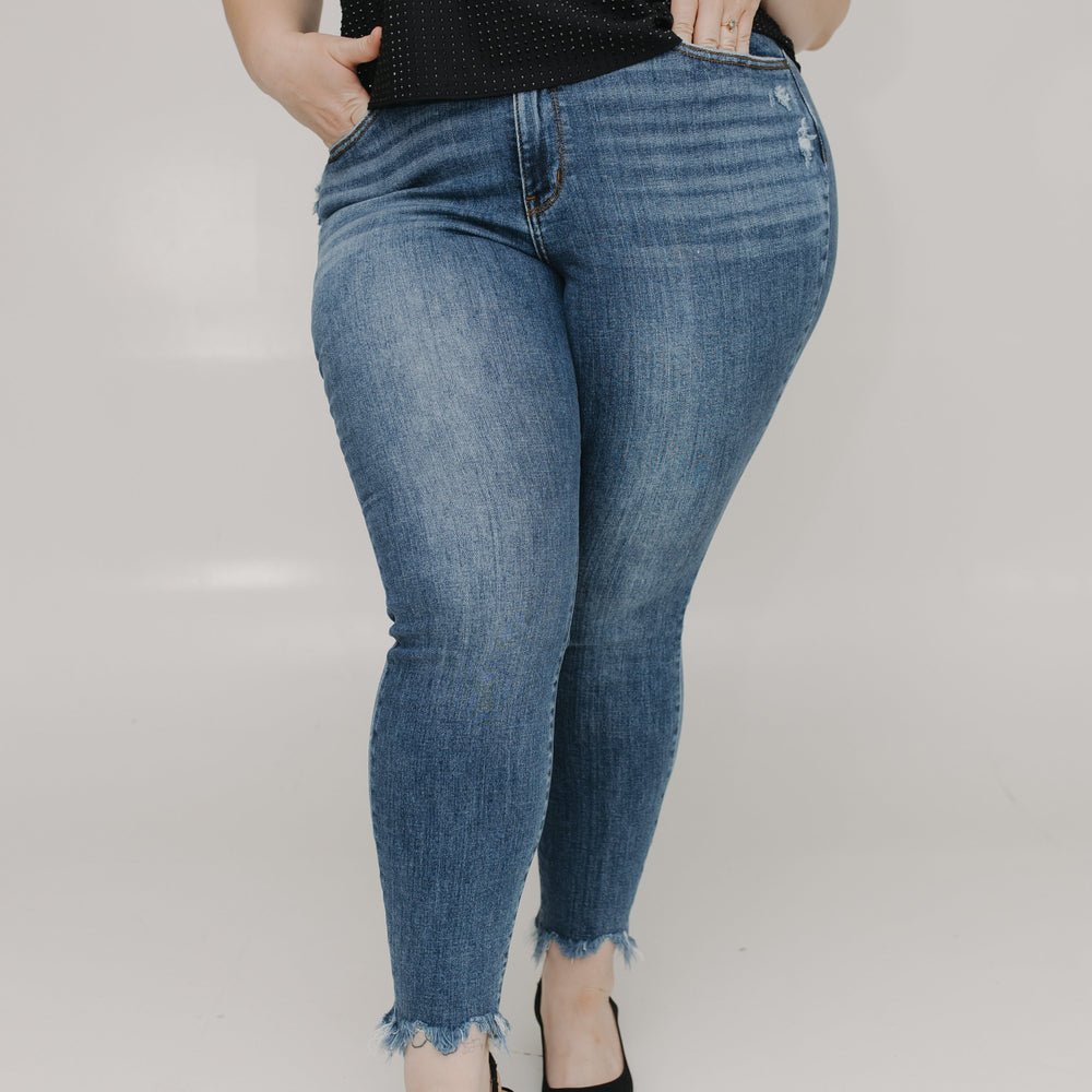Person wearing blue jeans and a black top on a plain background