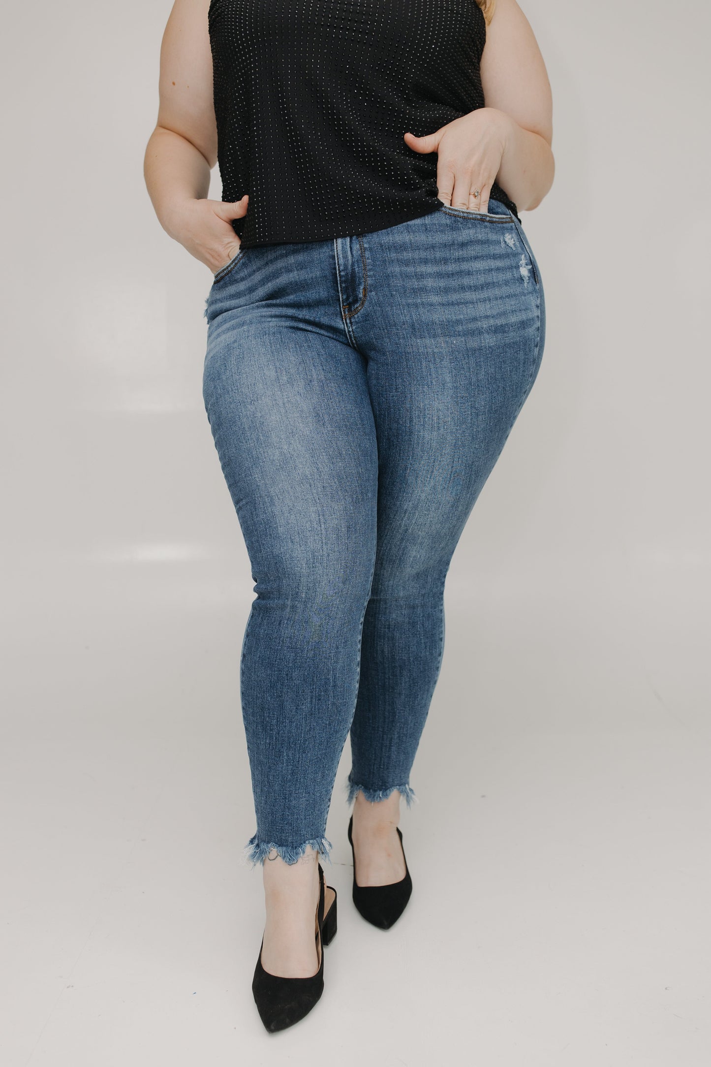 Person wearing blue jeans and a black top on a plain background