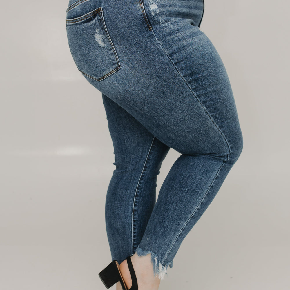 Person wearing blue jeans and black shoes on a plain background