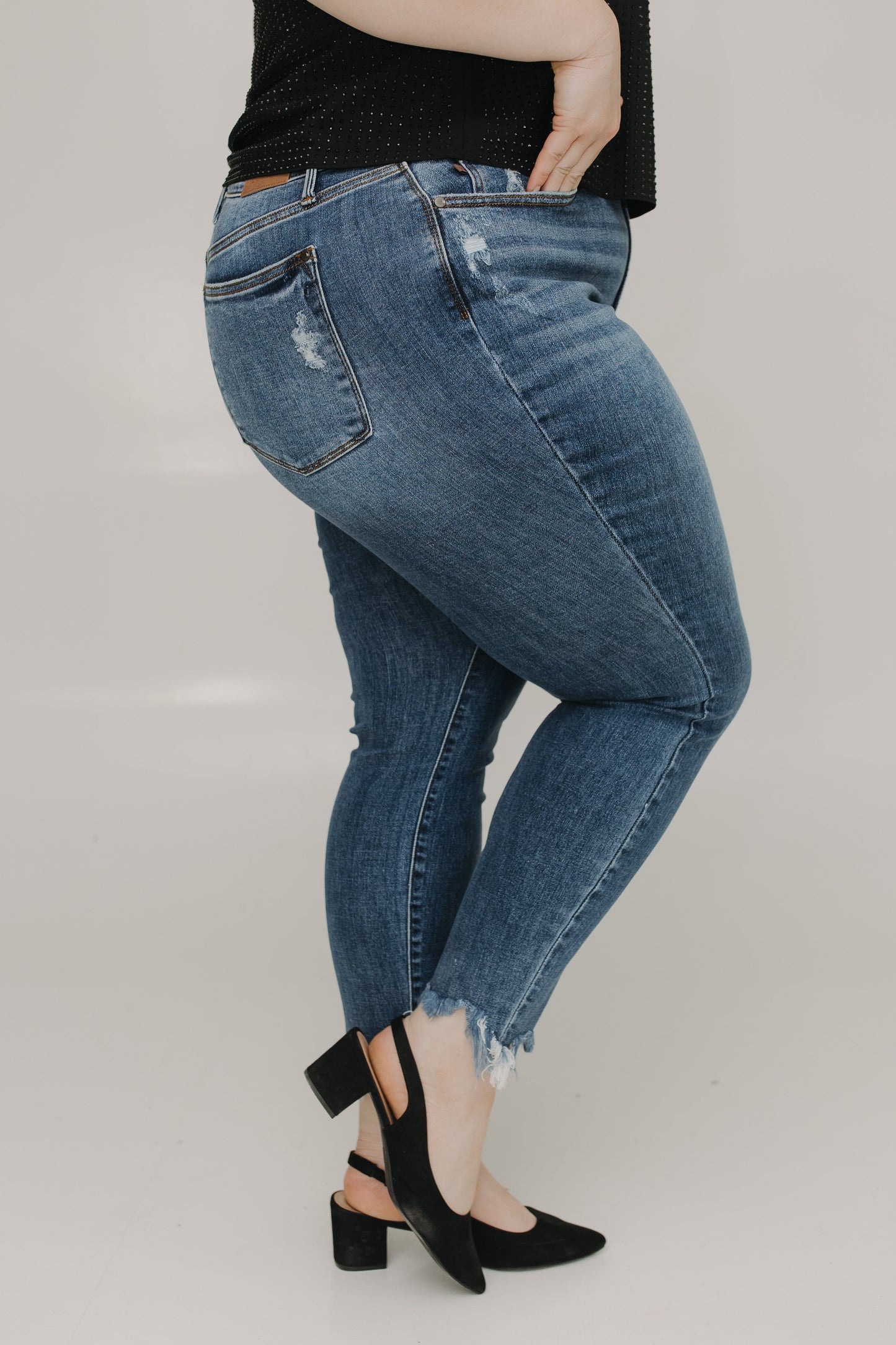 Person wearing blue jeans and black shoes on a plain background