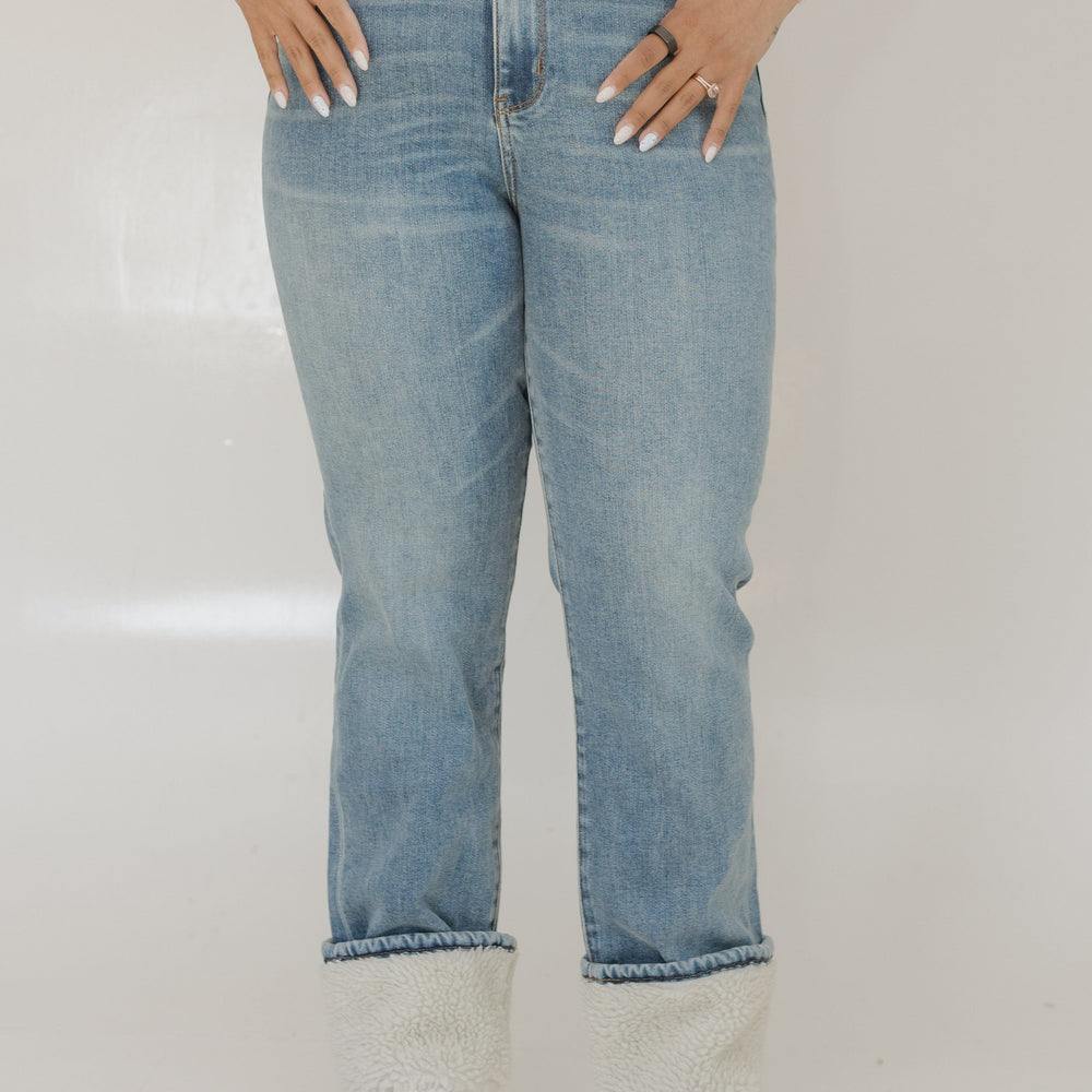 Person wearing blue jeans and a white shirt on a plain background