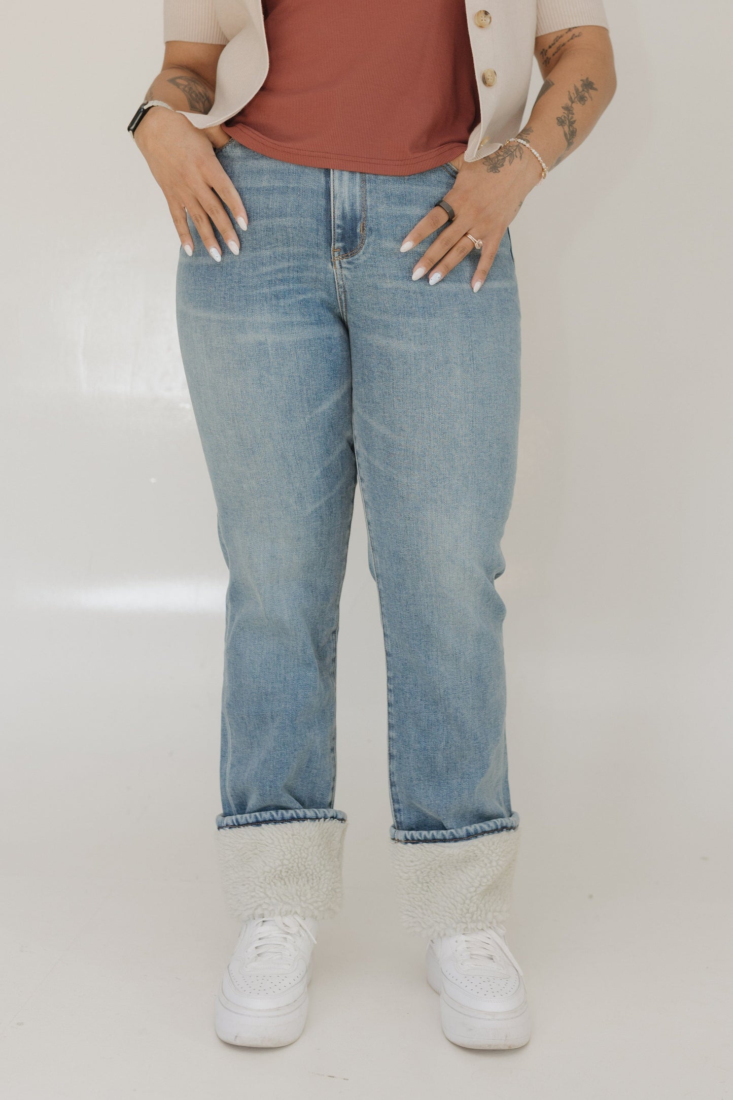 Person wearing blue jeans and a white shirt on a plain background
