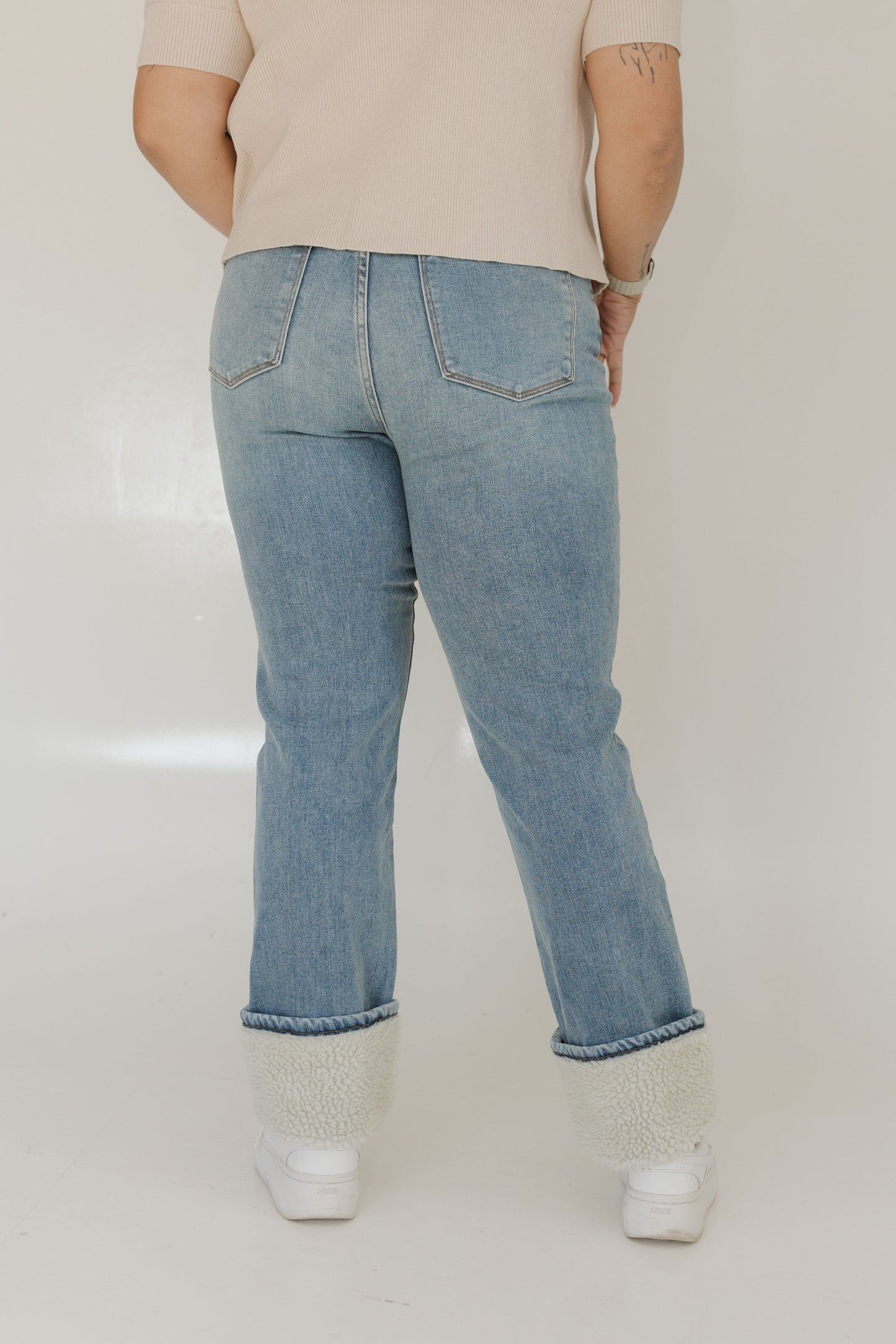 Person wearing light blue jeans on a plain background