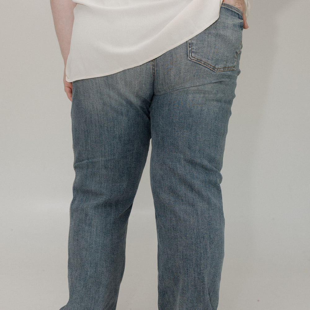 Person wearing blue jeans and a white shirt on a plain background