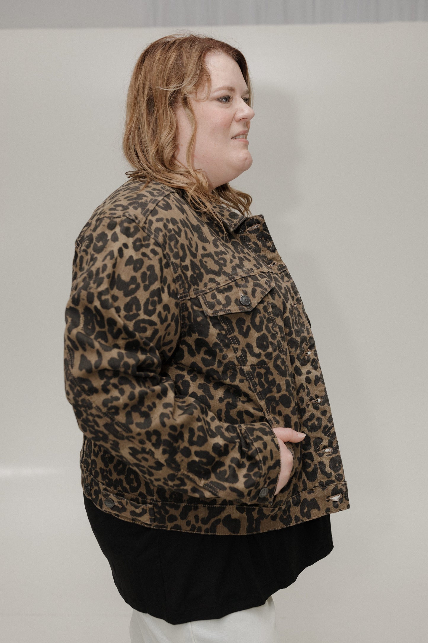 Person wearing a leopard print jacket against a plain background