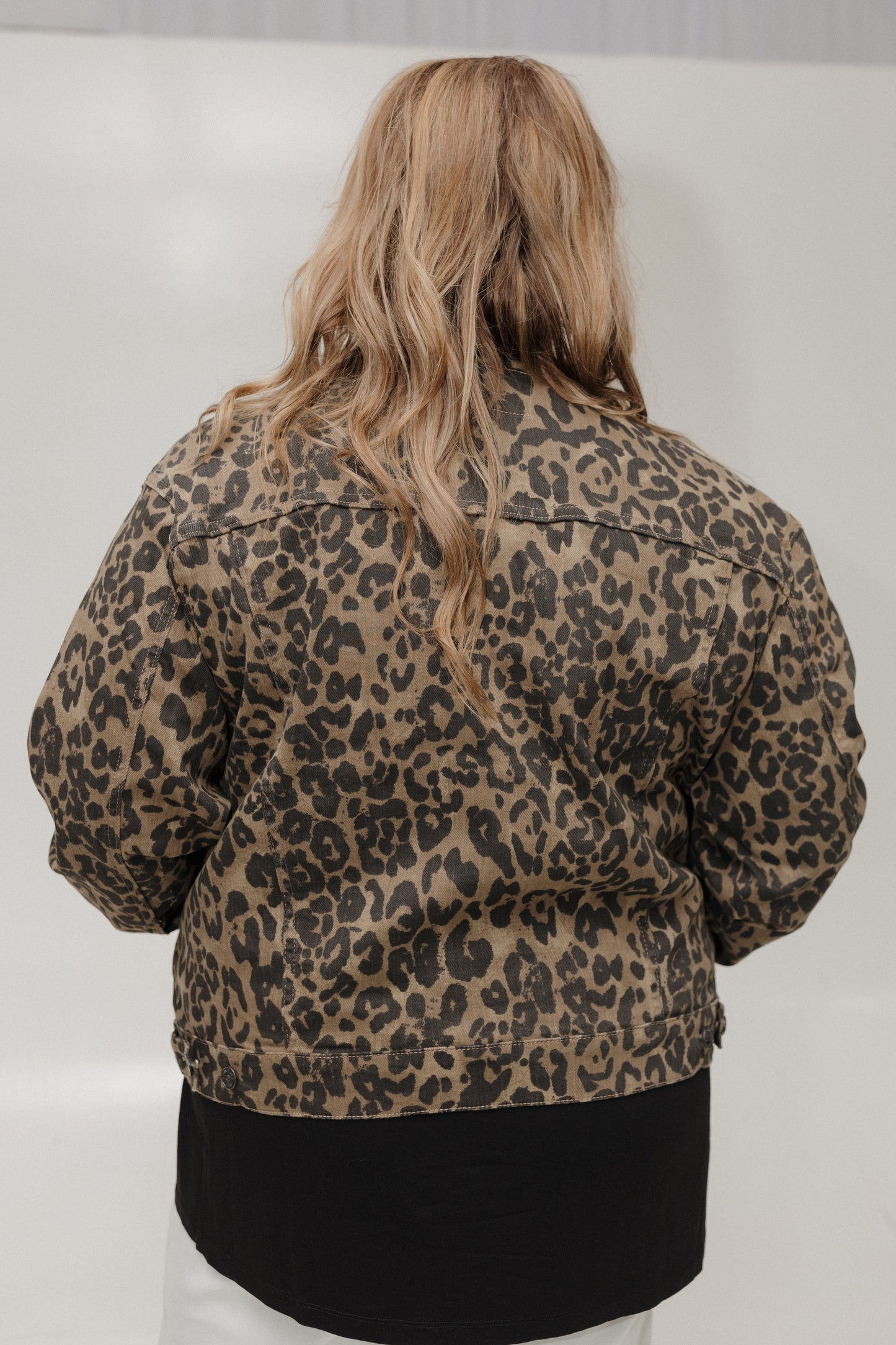 Person wearing a leopard print jacket from behind on a plain background