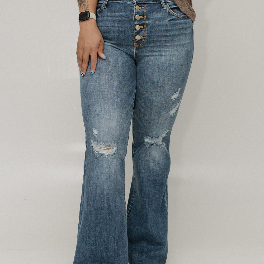 Person wearing blue distressed jeans with a plain background