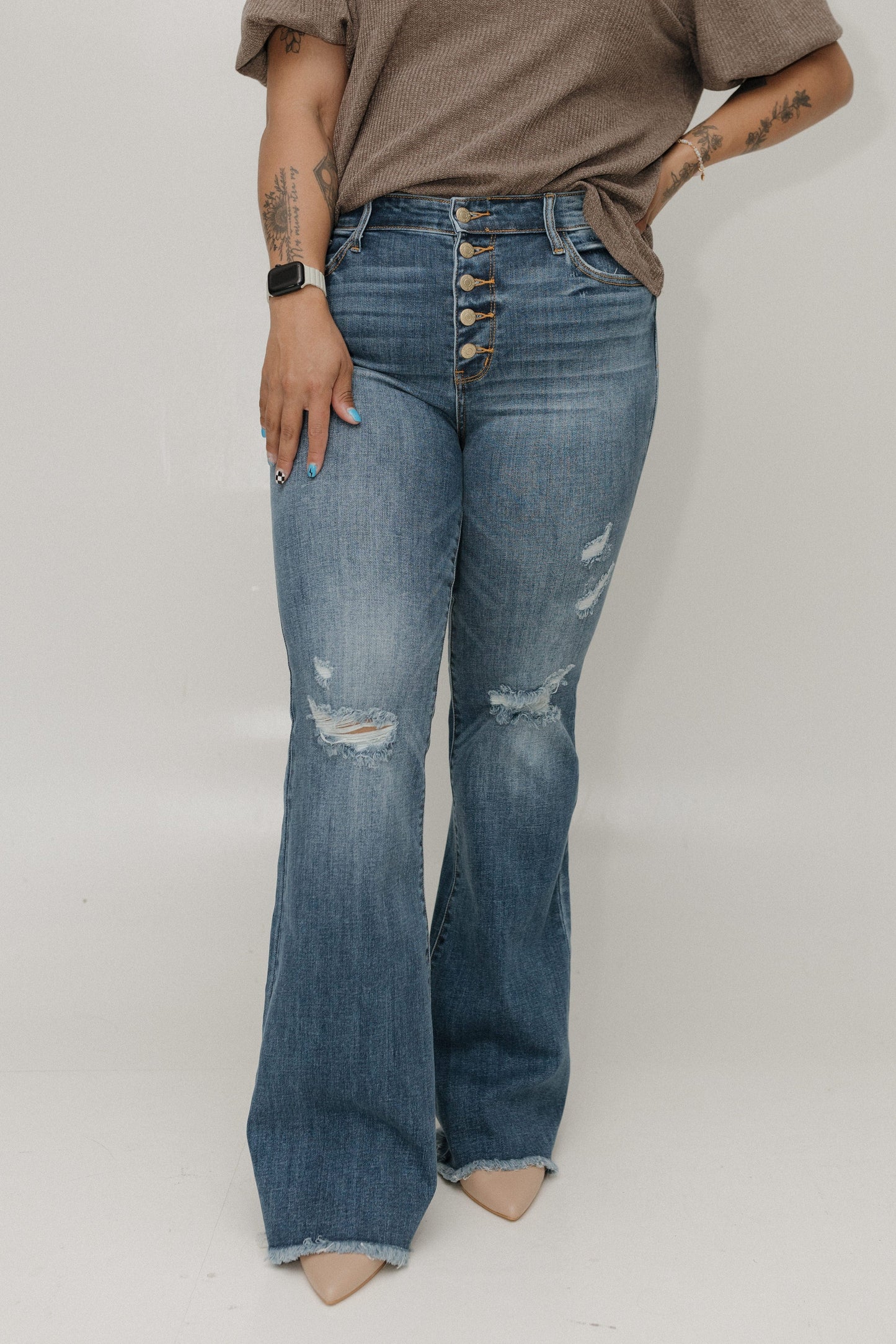 Person wearing blue distressed jeans with a plain background