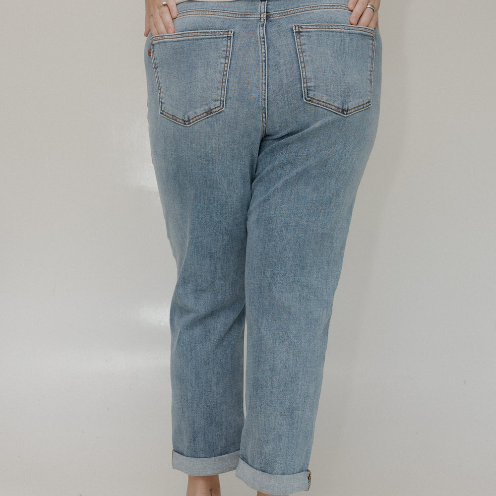 Person wearing light blue jeans and a beige top on a plain background