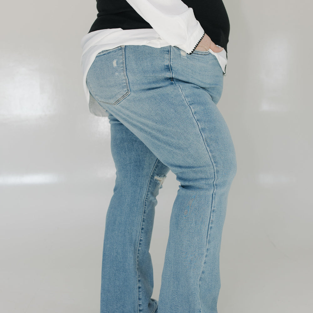 Person wearing light blue jeans and a black and white top on a plain background