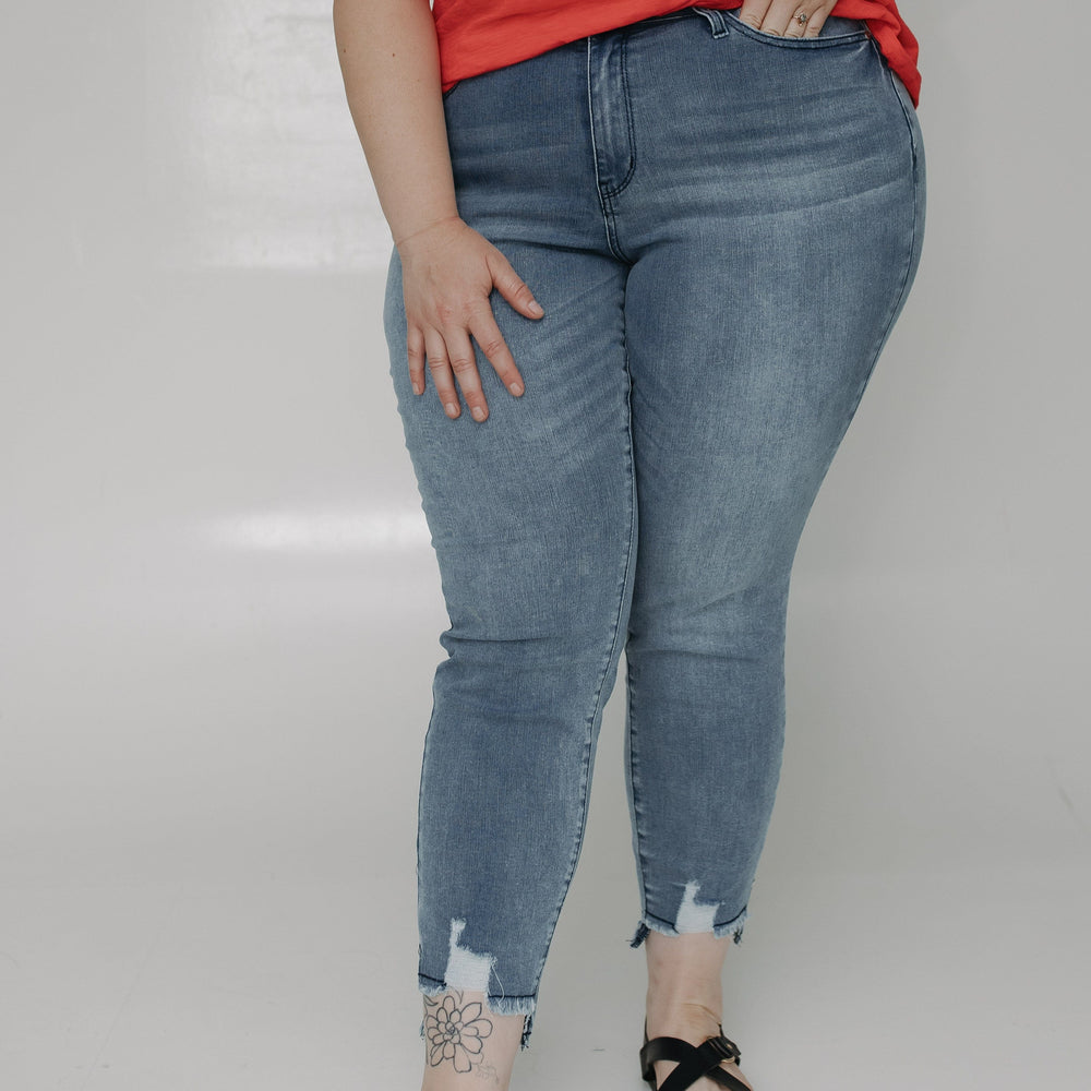 Person wearing a red shirt and blue jeans on a plain background