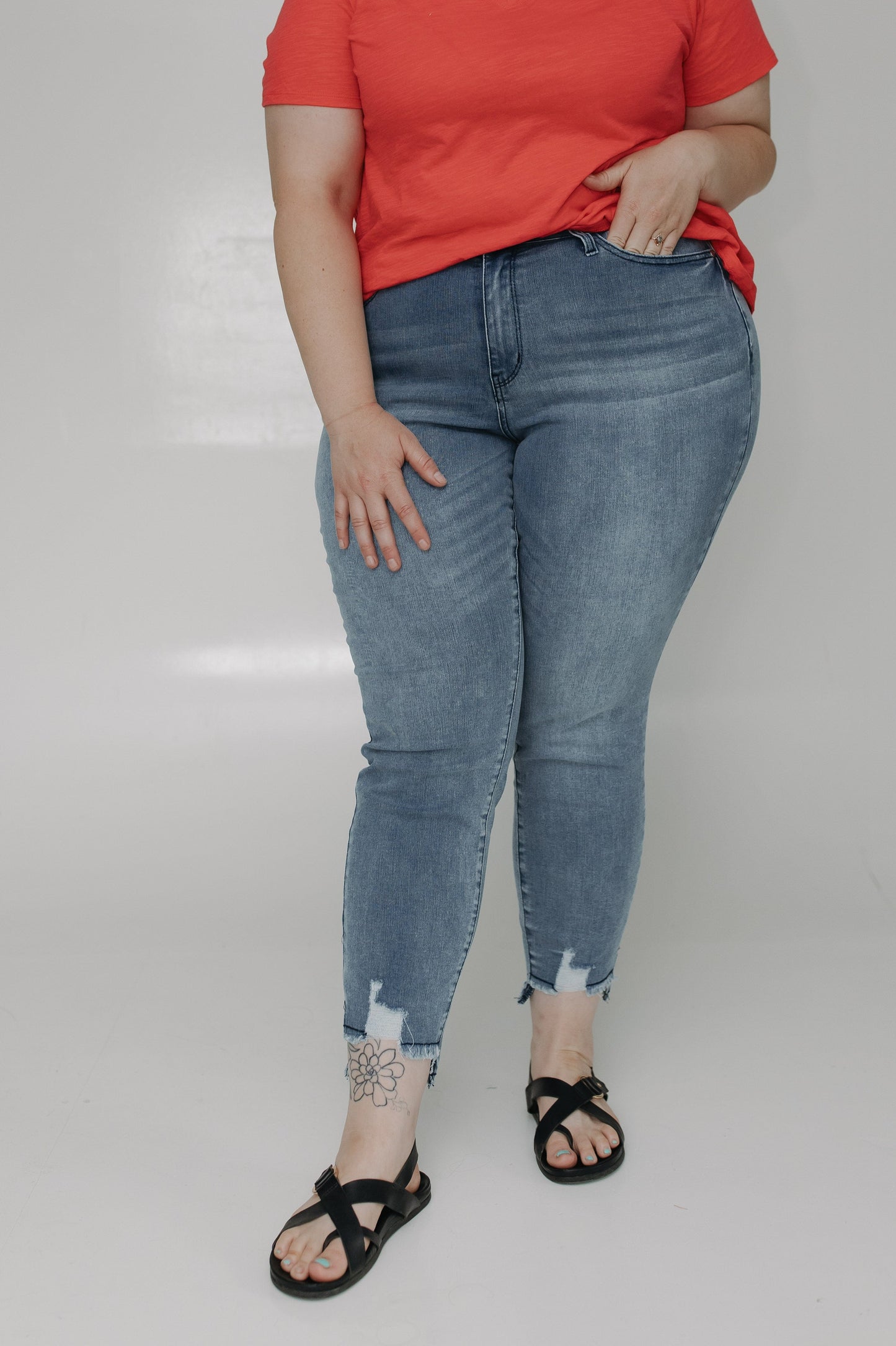 Person wearing a red shirt and blue jeans on a plain background