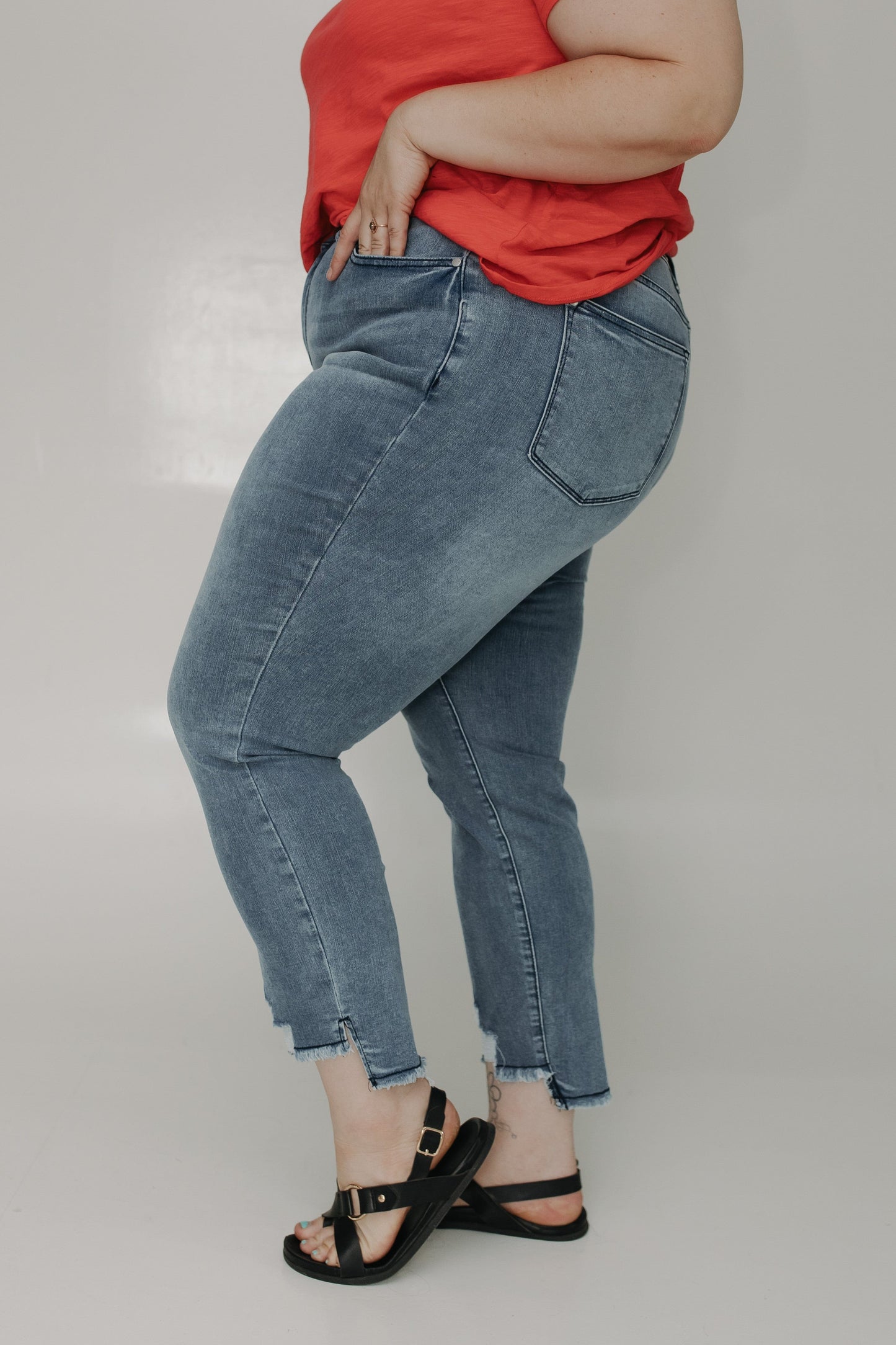 Person wearing blue jeans and a red top on a plain background