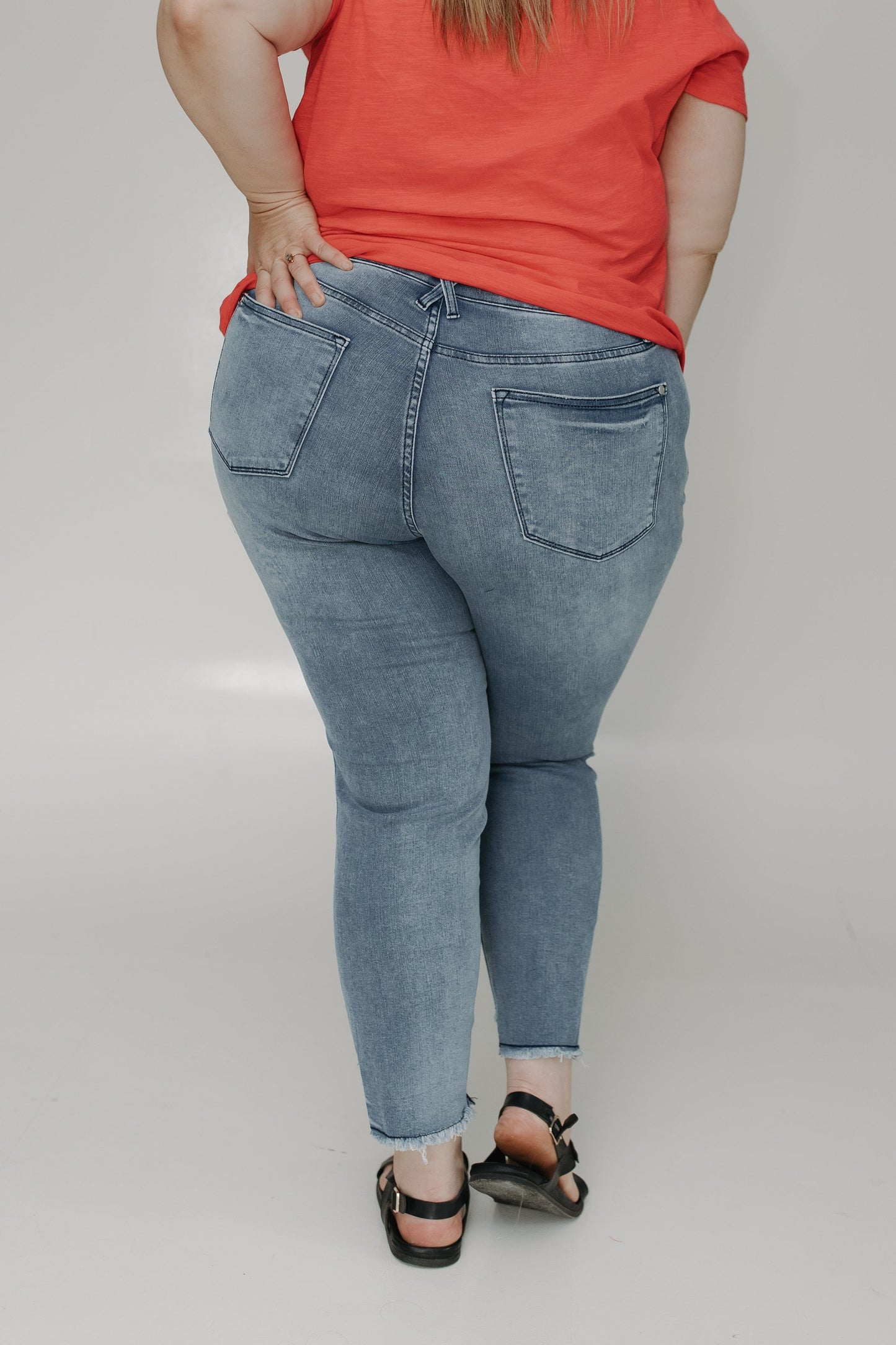 Person wearing blue jeans and a red top on a plain background