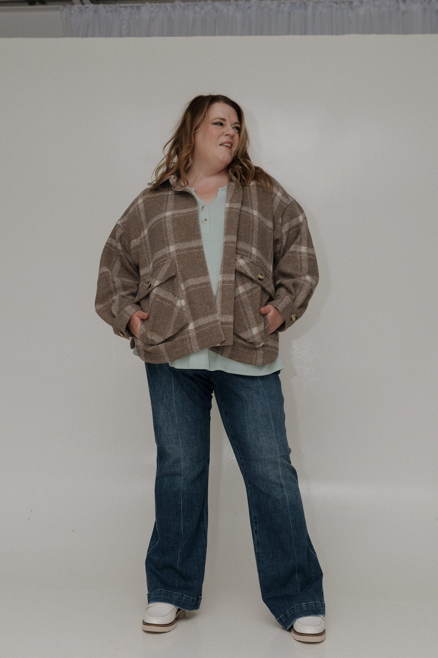 Person wearing a plaid jacket and jeans on a white background