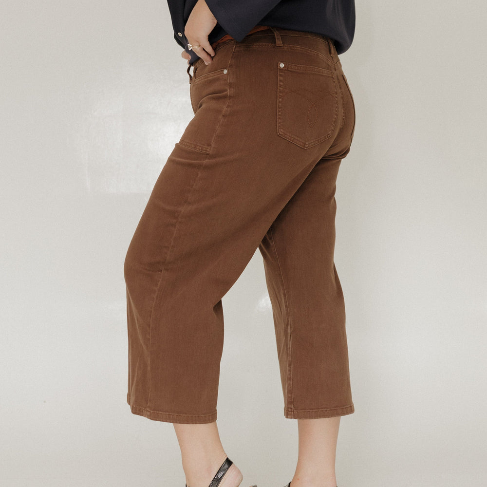 Person wearing brown pants and black shoes on a white background