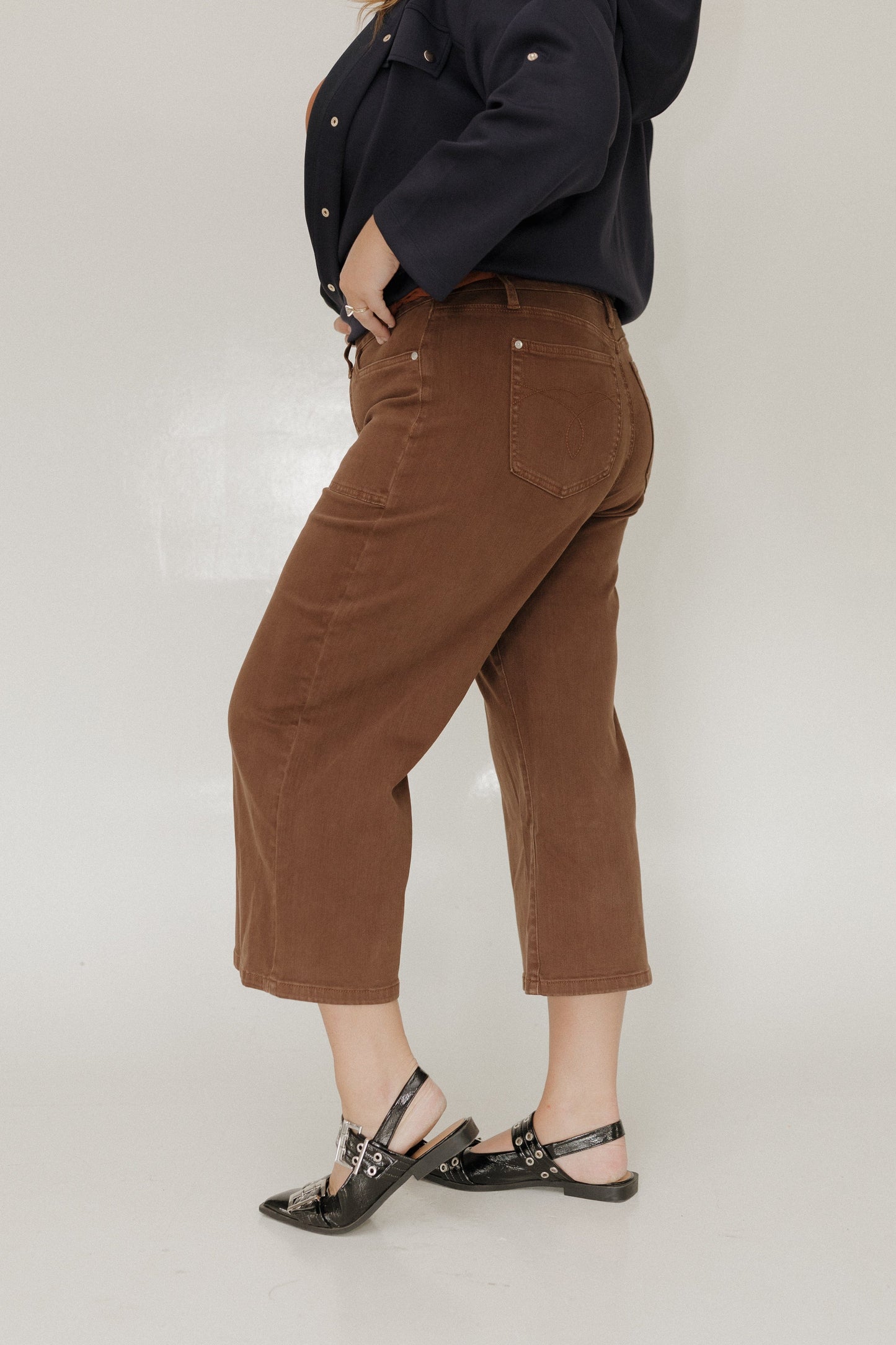 Person wearing brown pants and black shoes on a white background