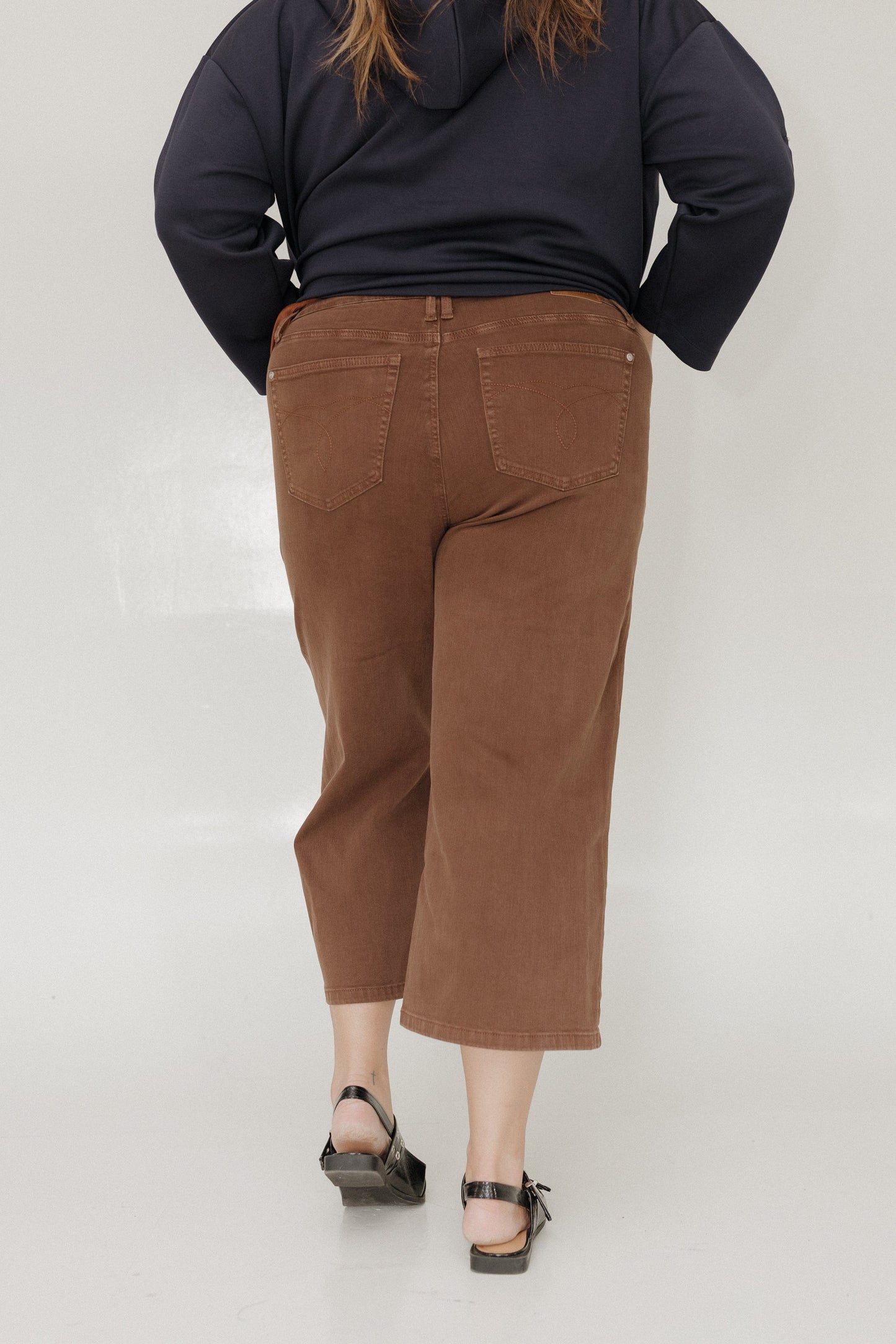 Person wearing brown pants and a dark top on a white background