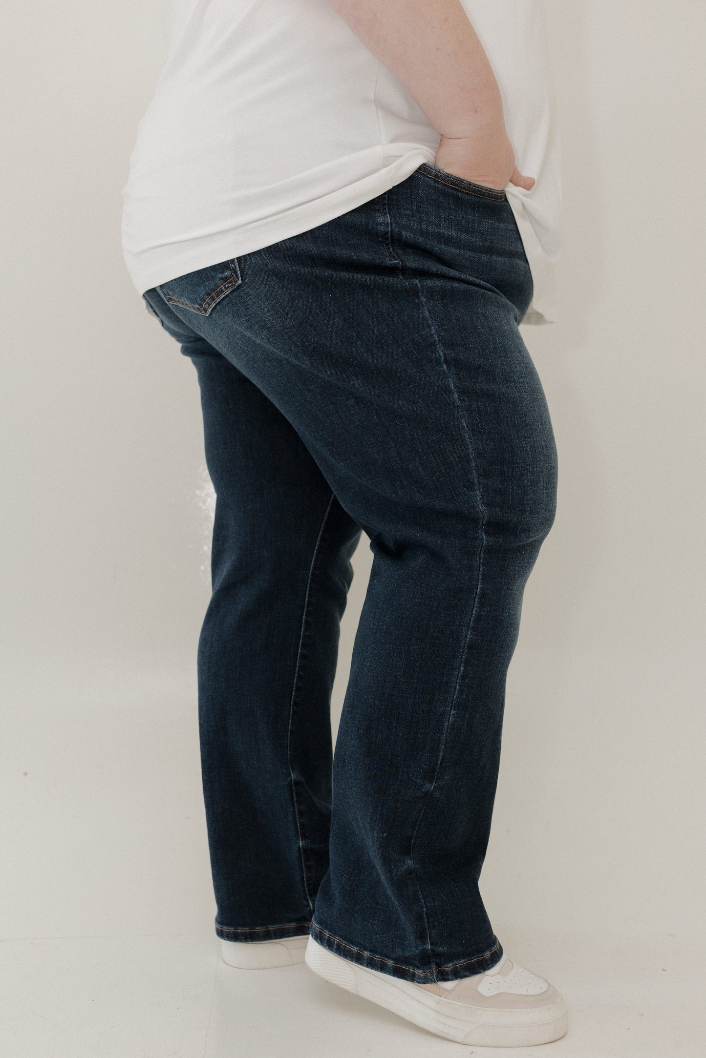 Person wearing blue jeans and a white shirt on a plain background