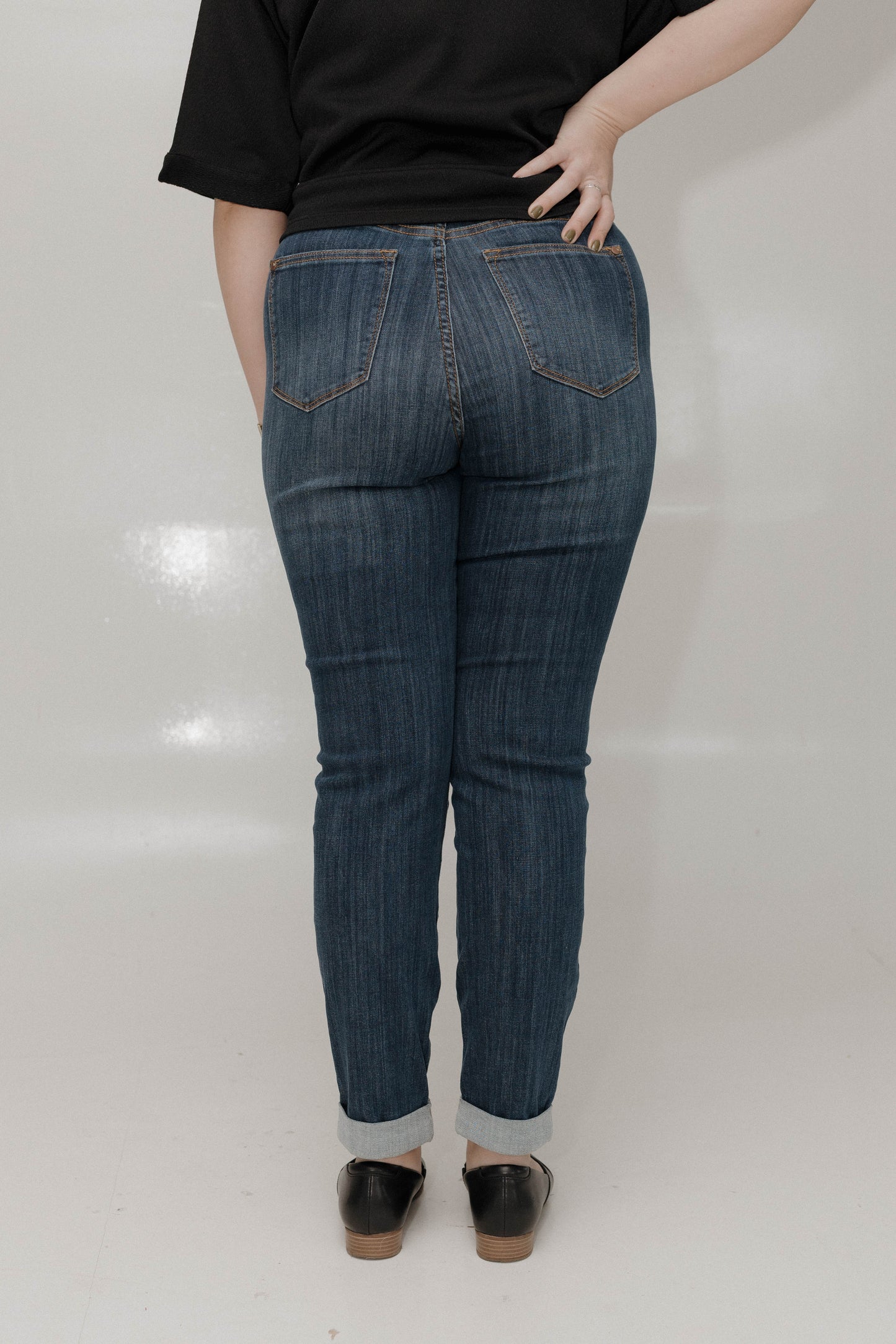 Person wearing blue jeans and black shoes on a white background