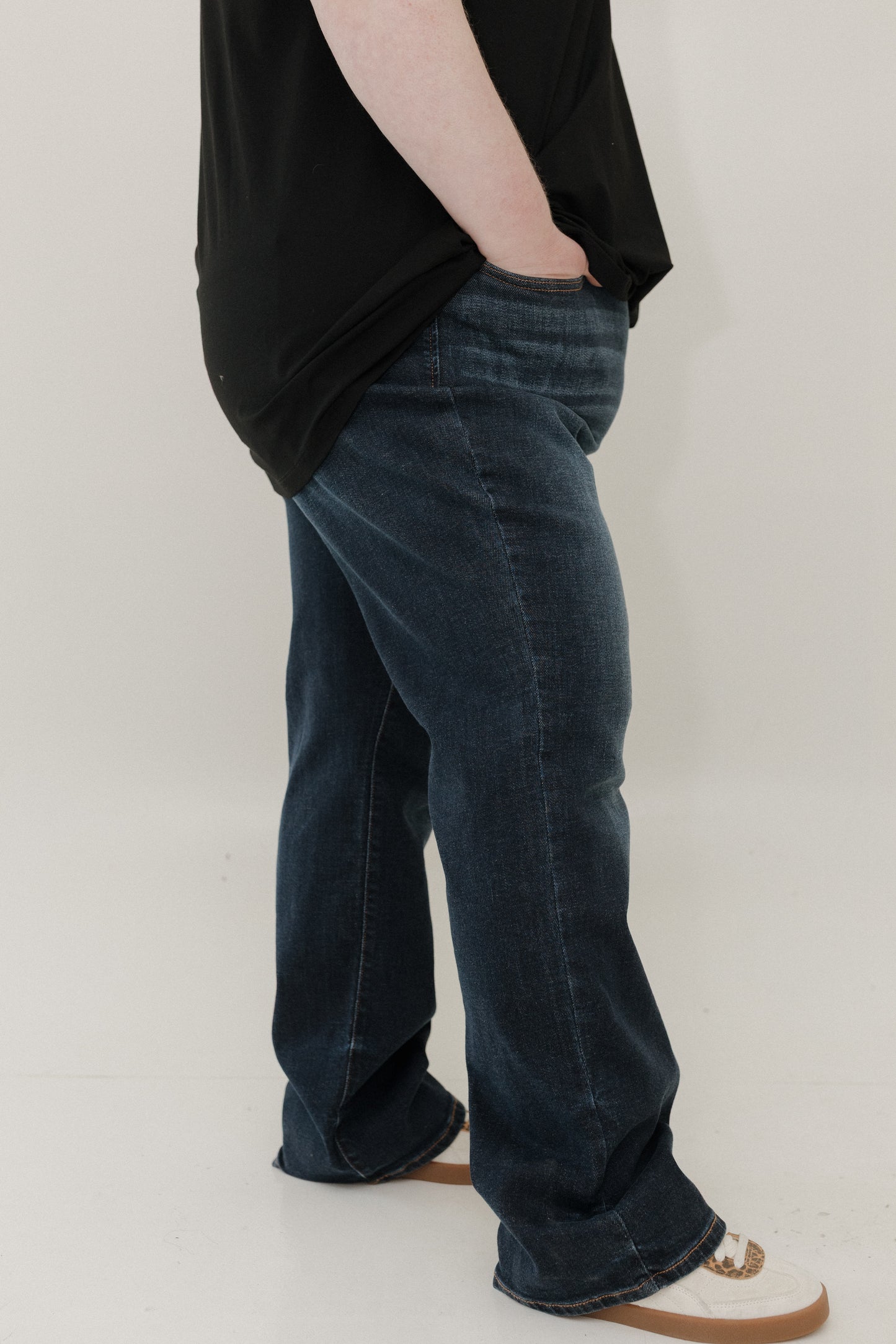 Person wearing dark blue jeans and a black top on a plain background