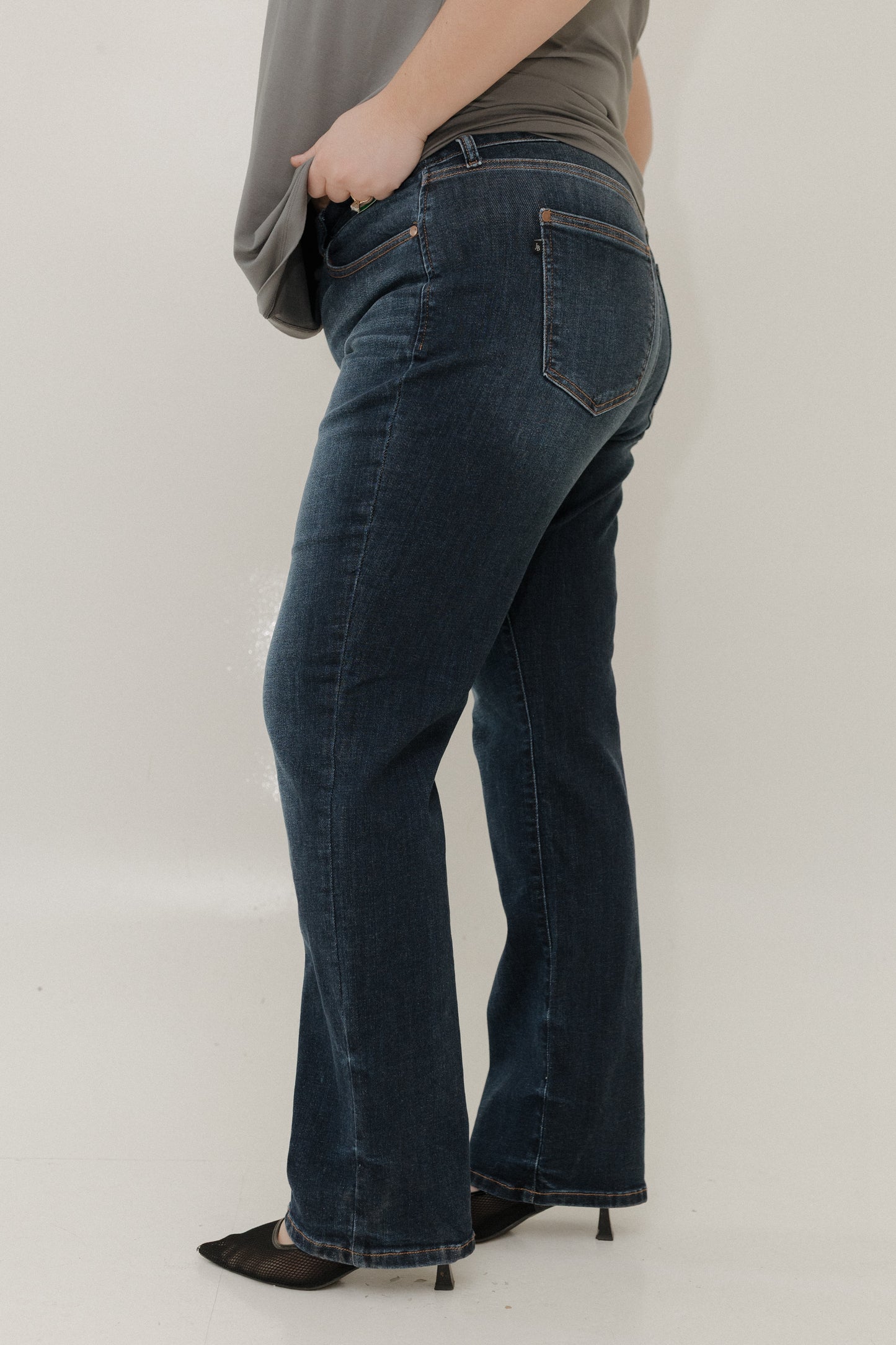 Person wearing dark blue jeans against a plain background