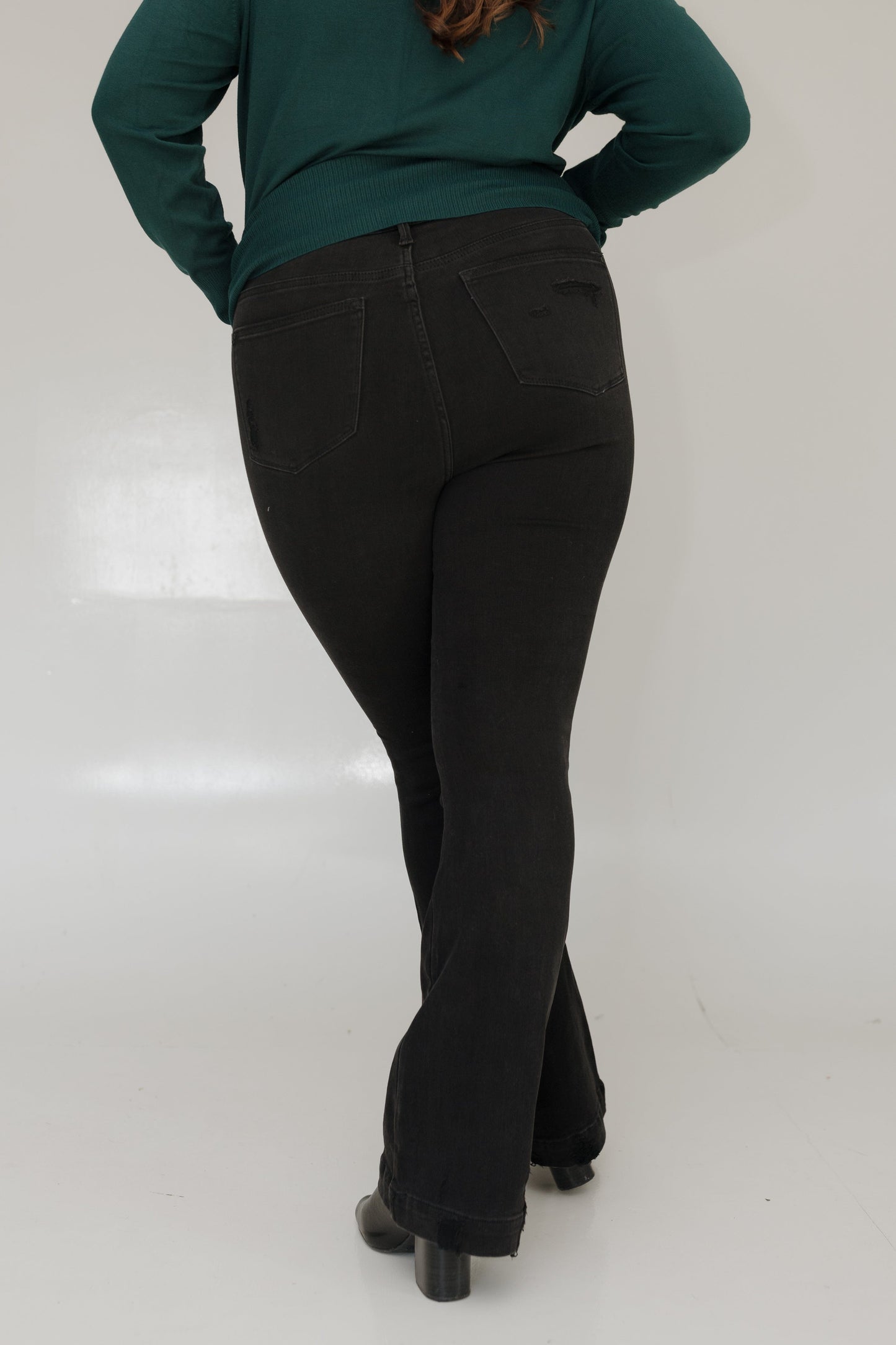 Person wearing a green sweater and black pants on a white background