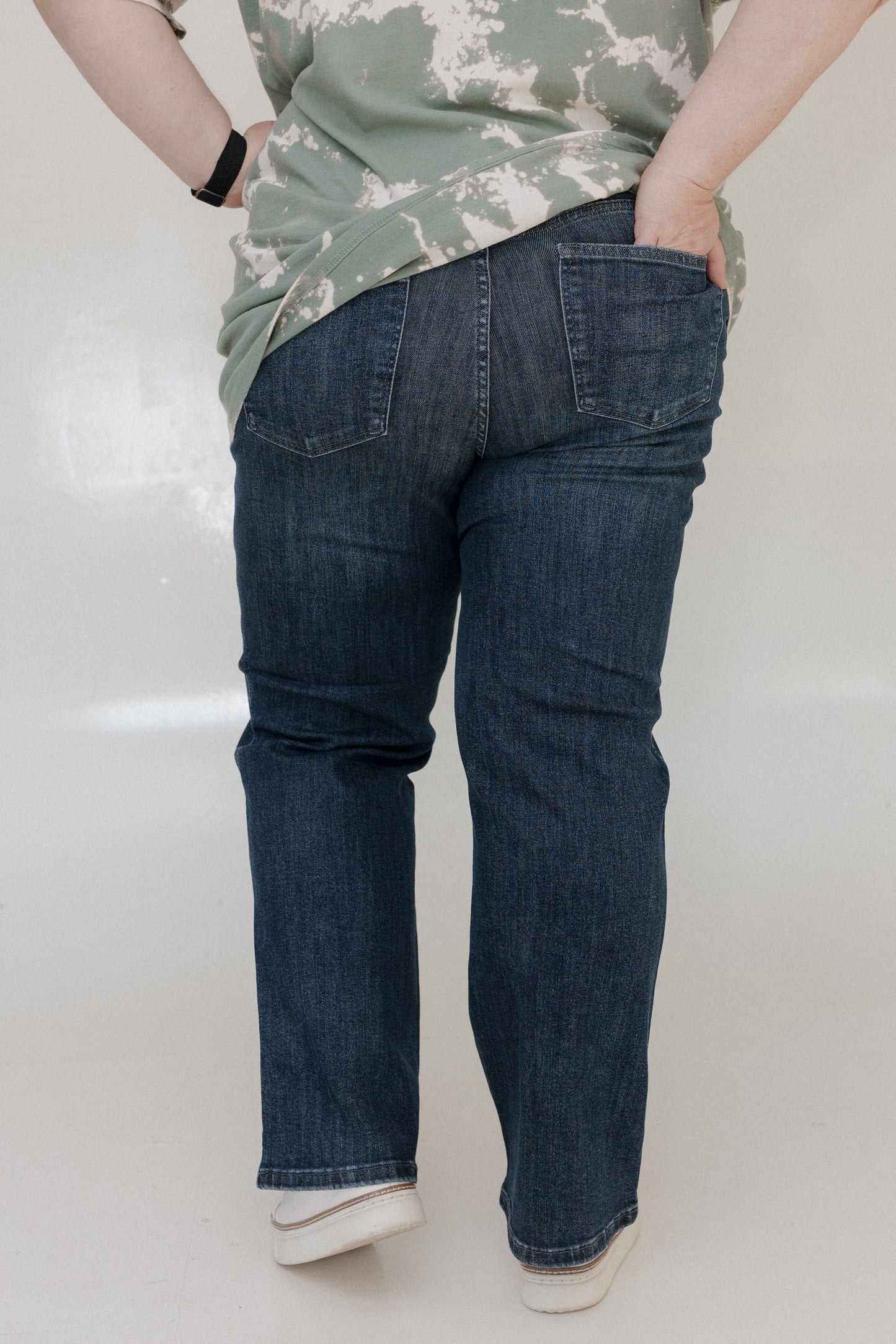 Person wearing blue jeans and a camouflage shirt on a white background