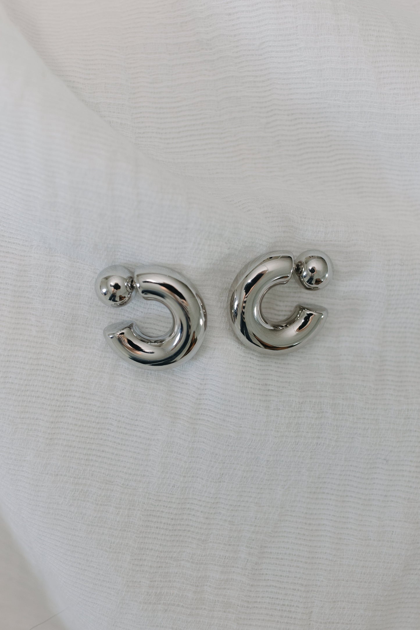 Silver moon-shaped earrings on a white background