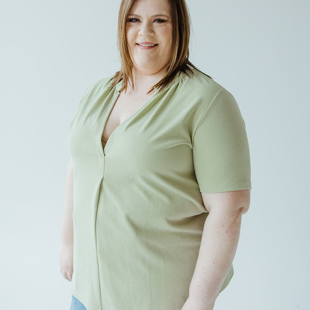 Woman with shoulder-length brown hair wearing a Love Marlow KNIT BLOUSE WITH MANDARIN COLLAR and blue jeans stands against a plain white background.