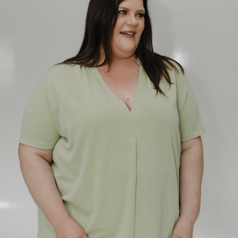 Woman wearing a light green top against a plain background