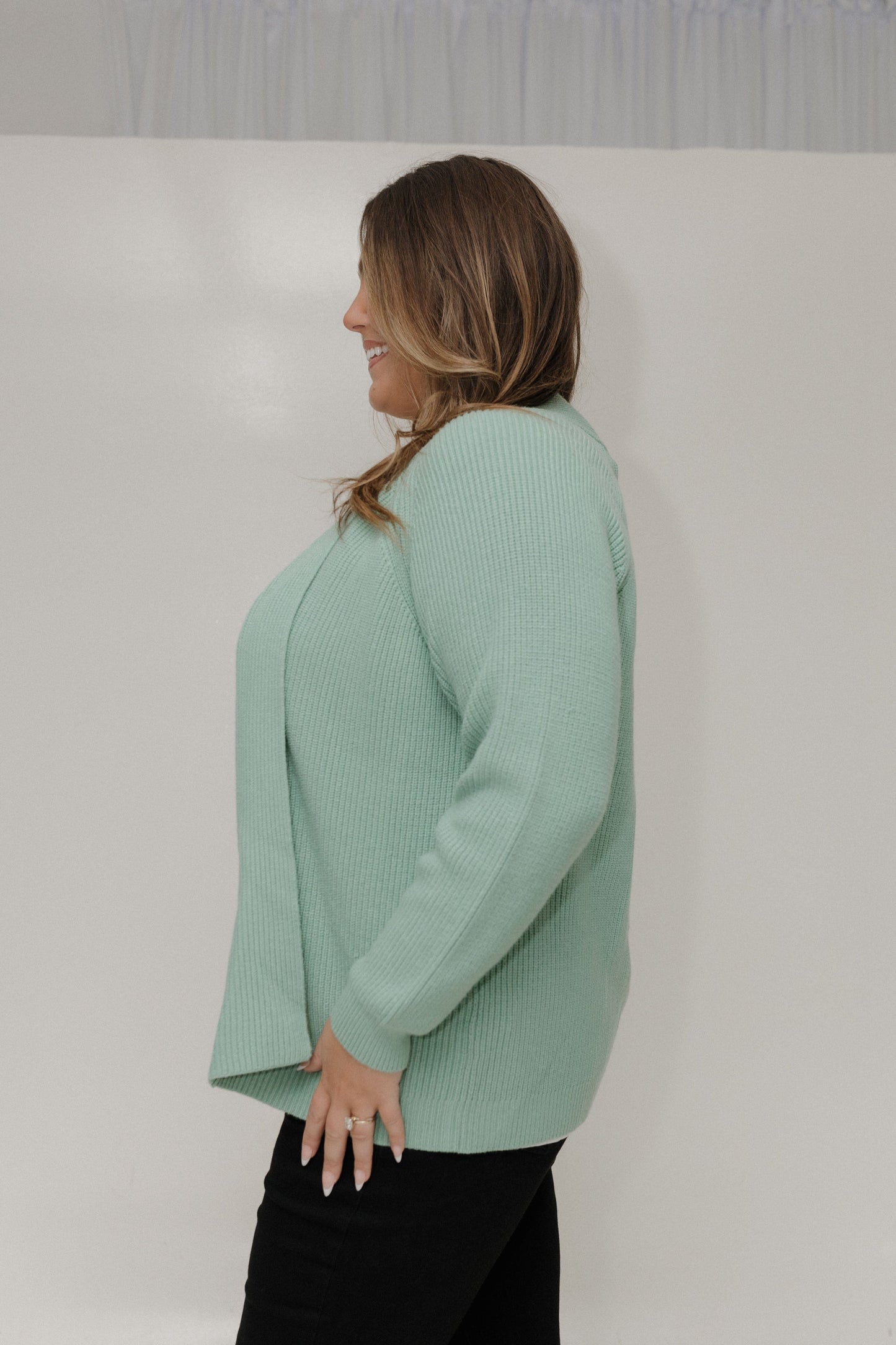 Woman wearing a light green sweater against a plain background