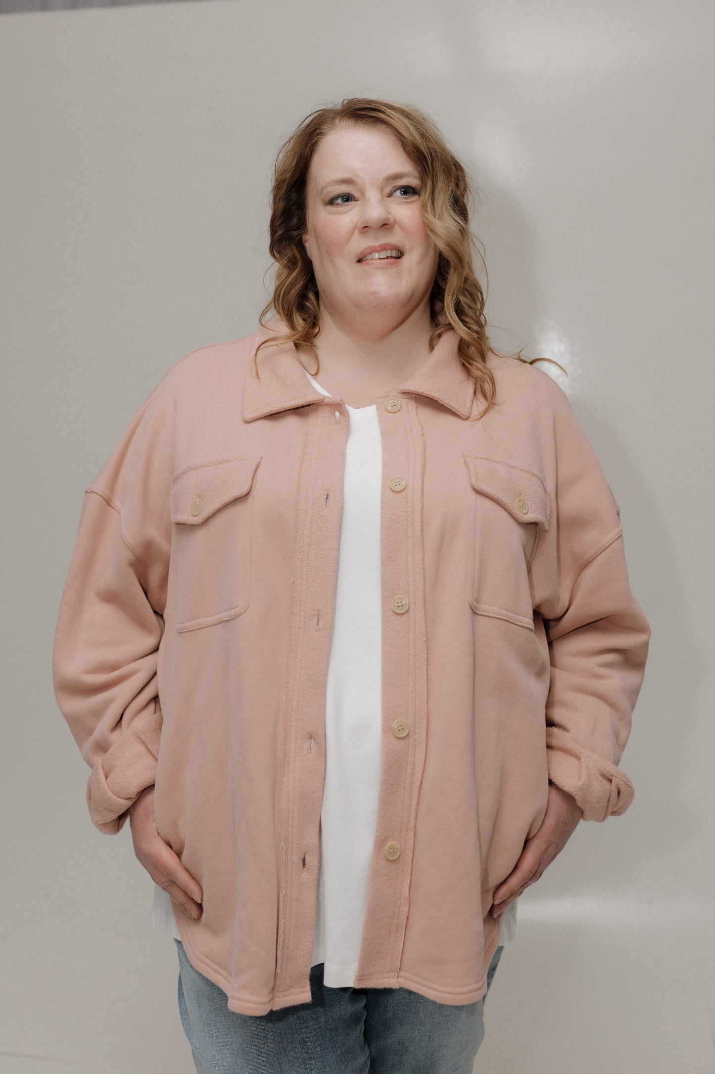 Person wearing a pink jacket over a white shirt with a plain background