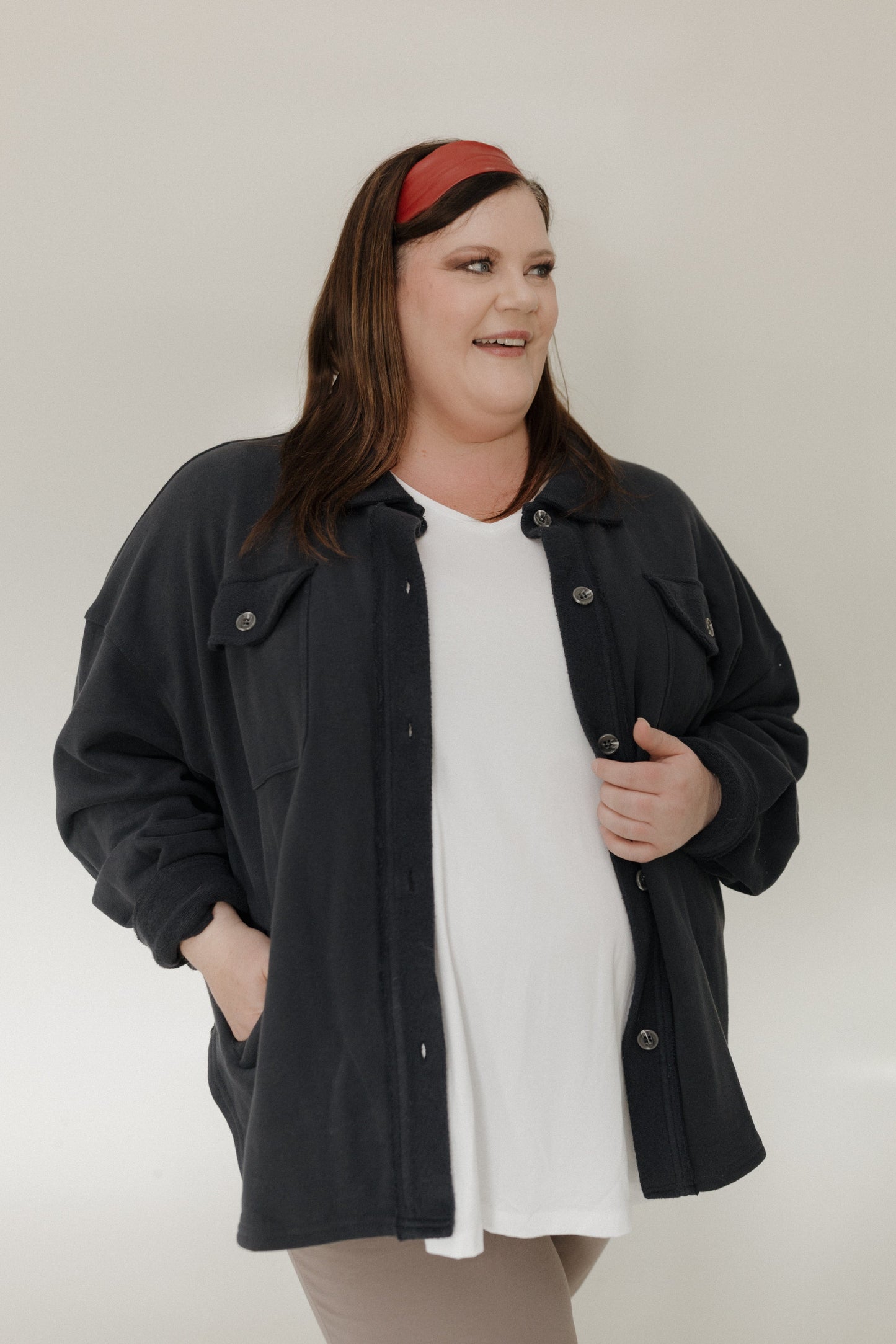 Woman wearing a black jacket over a white shirt with a plain background