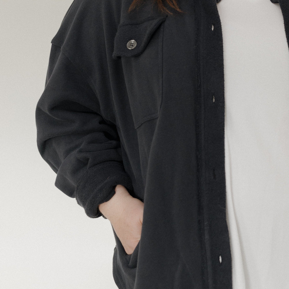 Person wearing a black jacket over a white shirt on a plain background